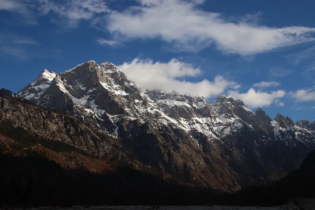 Ruige bergtoppen, deels bedekt met sneeuw, steken af tegen een helderblauwe hemel.
