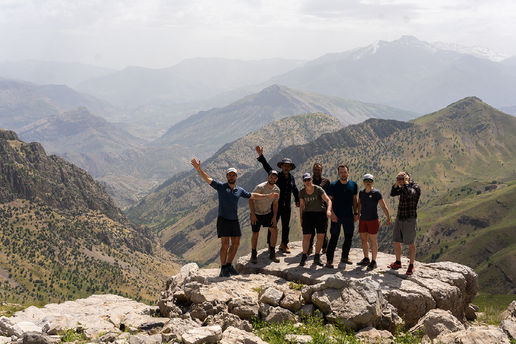 groep deelnemers poseert op een bergtop met uitgestrekt uitzicht over het ruige landschap van de Oukaïmeden