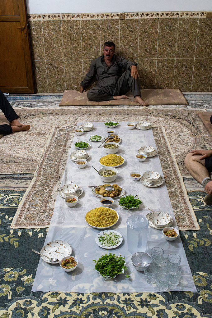 traditionele maaltijd op de grond met kleurrijke gerechten op een plastic kleed en mensen zittend op tapijten eromheen
