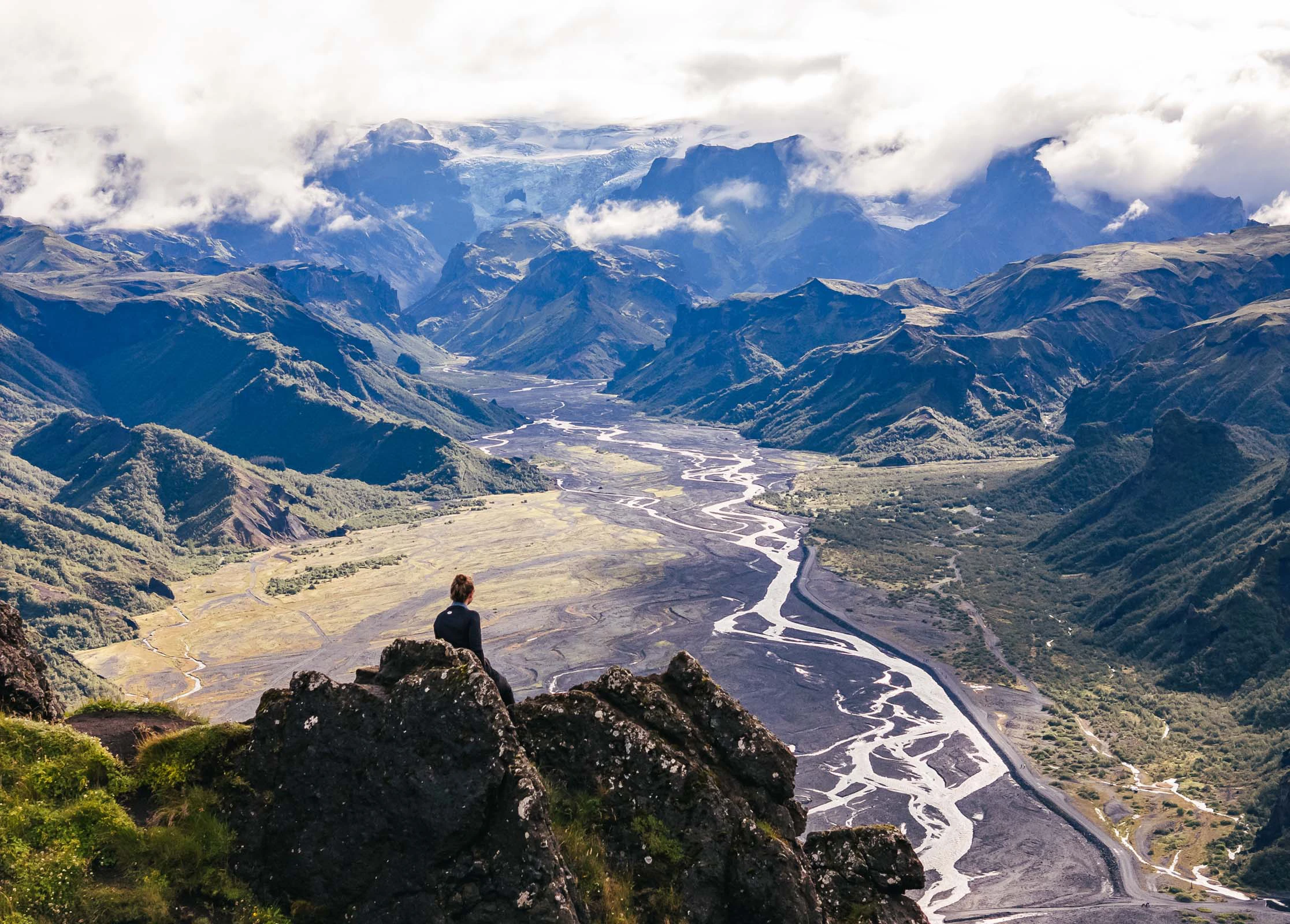 Wandelaar staat op een berg met uitzicht over een brede vallei