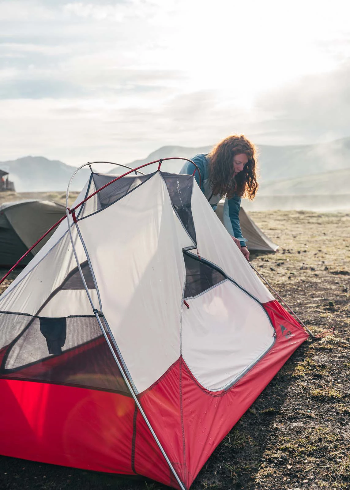 Vrouw zet een tent op in koud landschap
