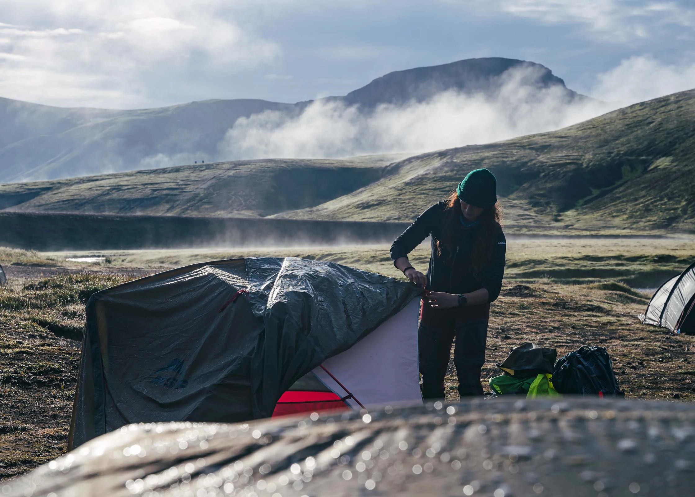 Kampeerders bij een tent in een mistig berggebied