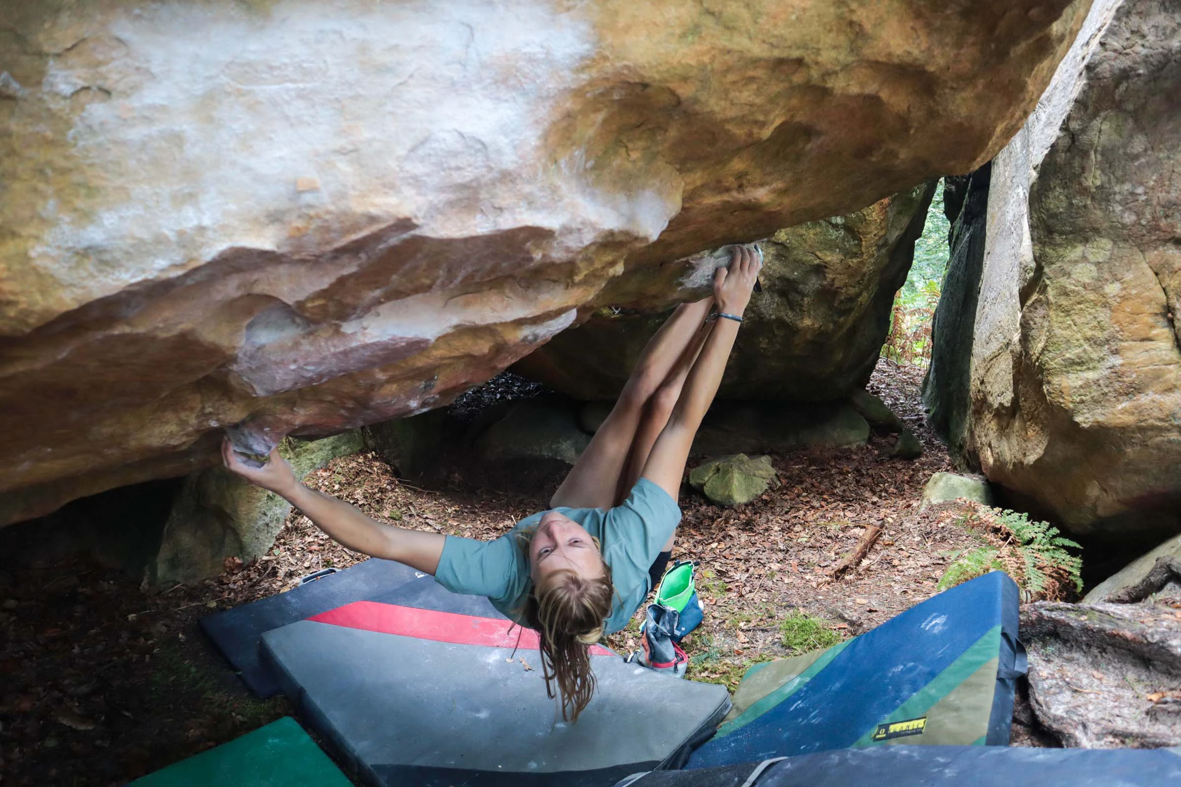 Klimmer die onder een lage rots hangt met crashpads