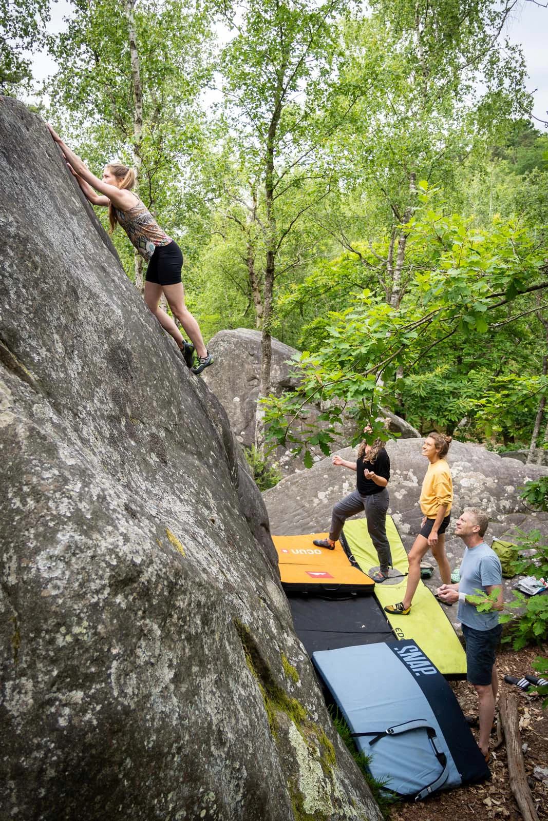 Klimmers rond een boulder met crashpads