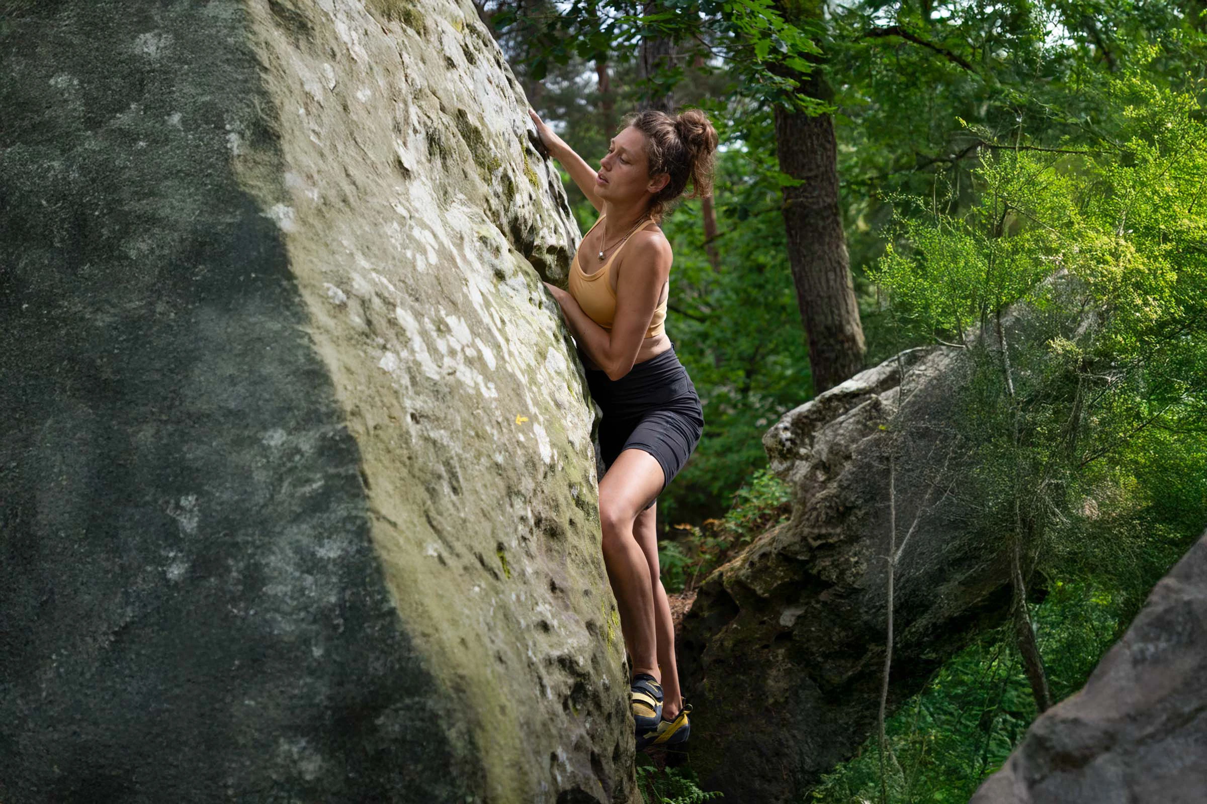 Vrouw bouldert op een grote rots in het bos