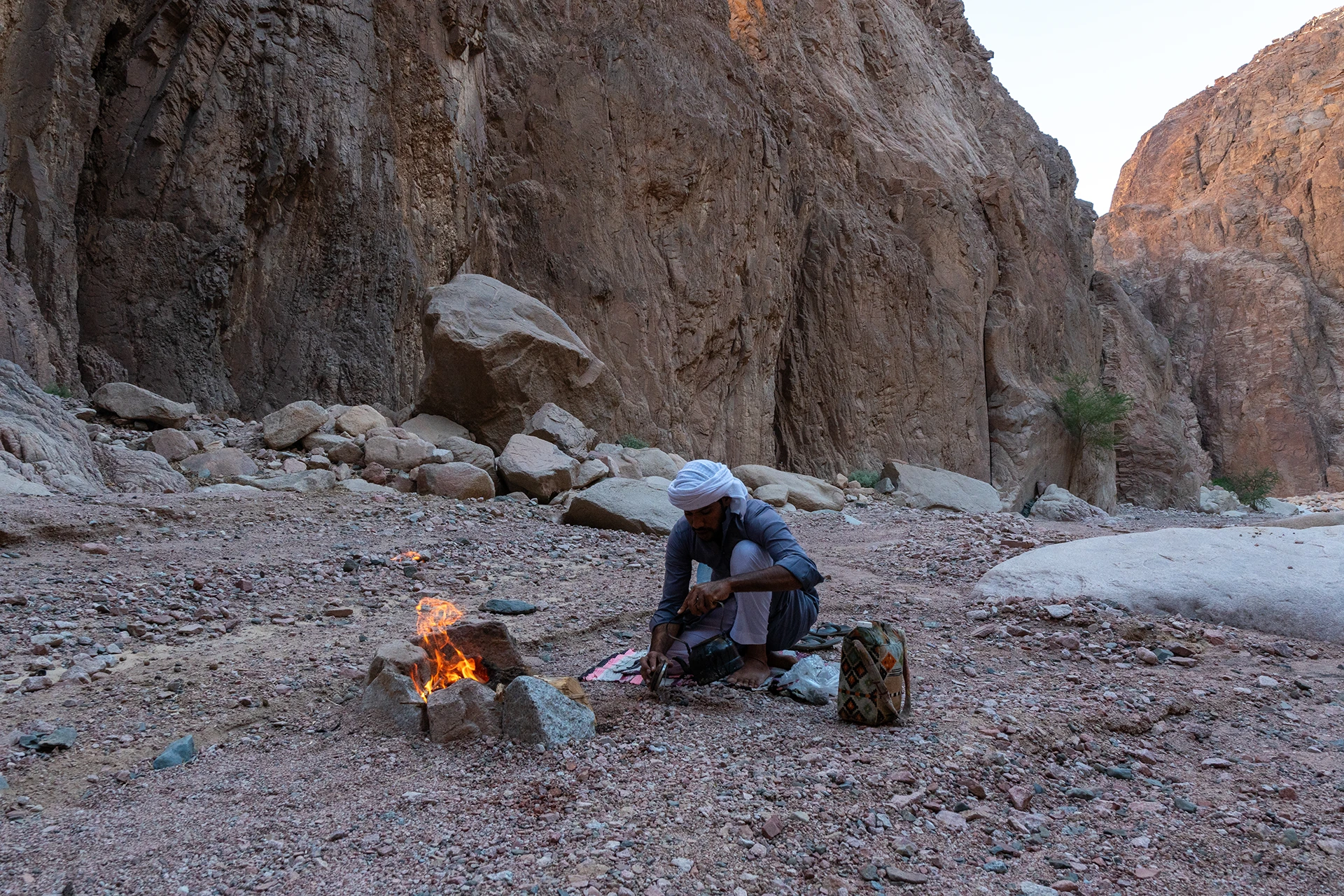 Man kookt bij een kampvuur in een droge kloof