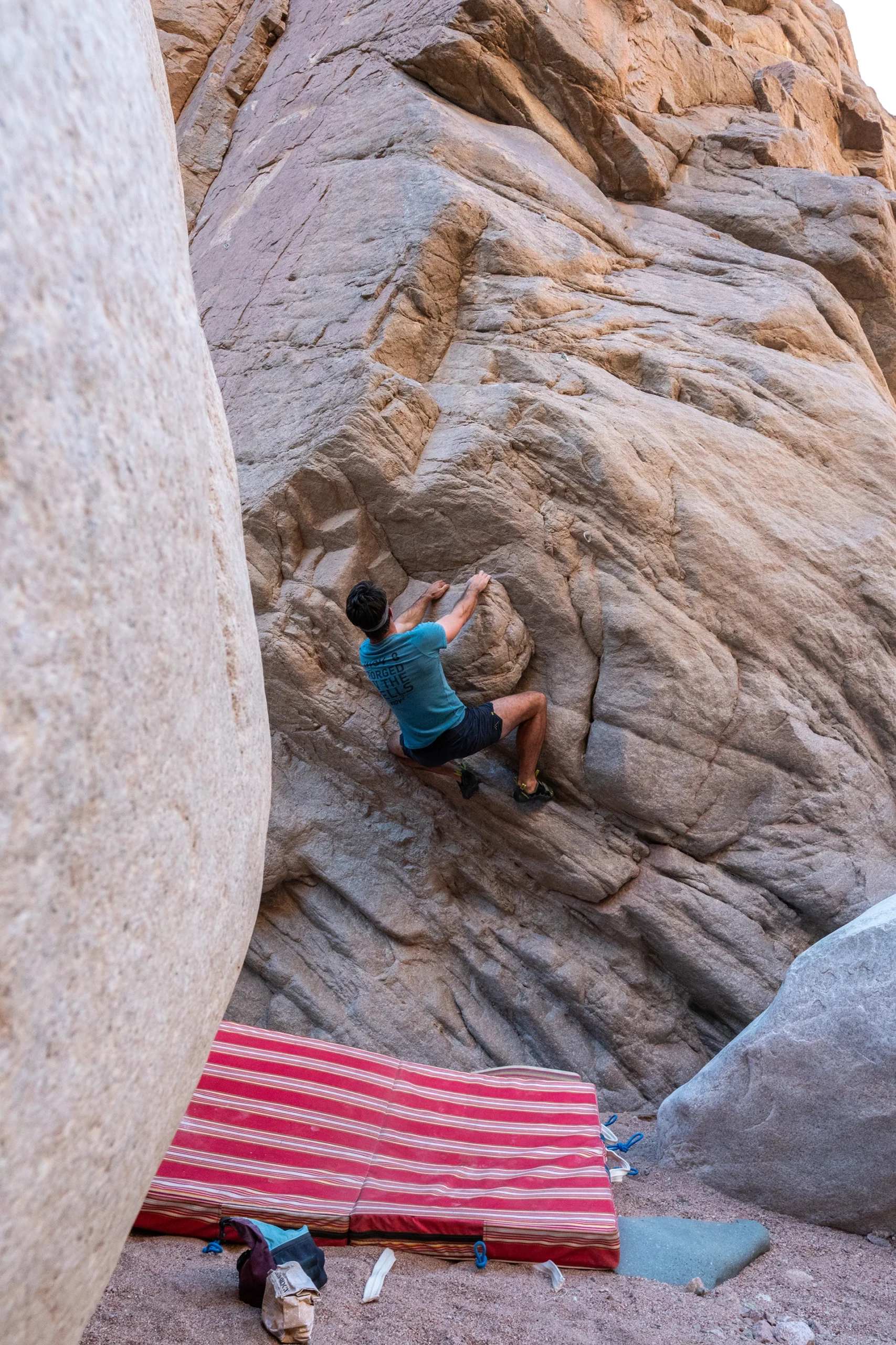 Klimmer zit op crashpad naast een rotsblok
