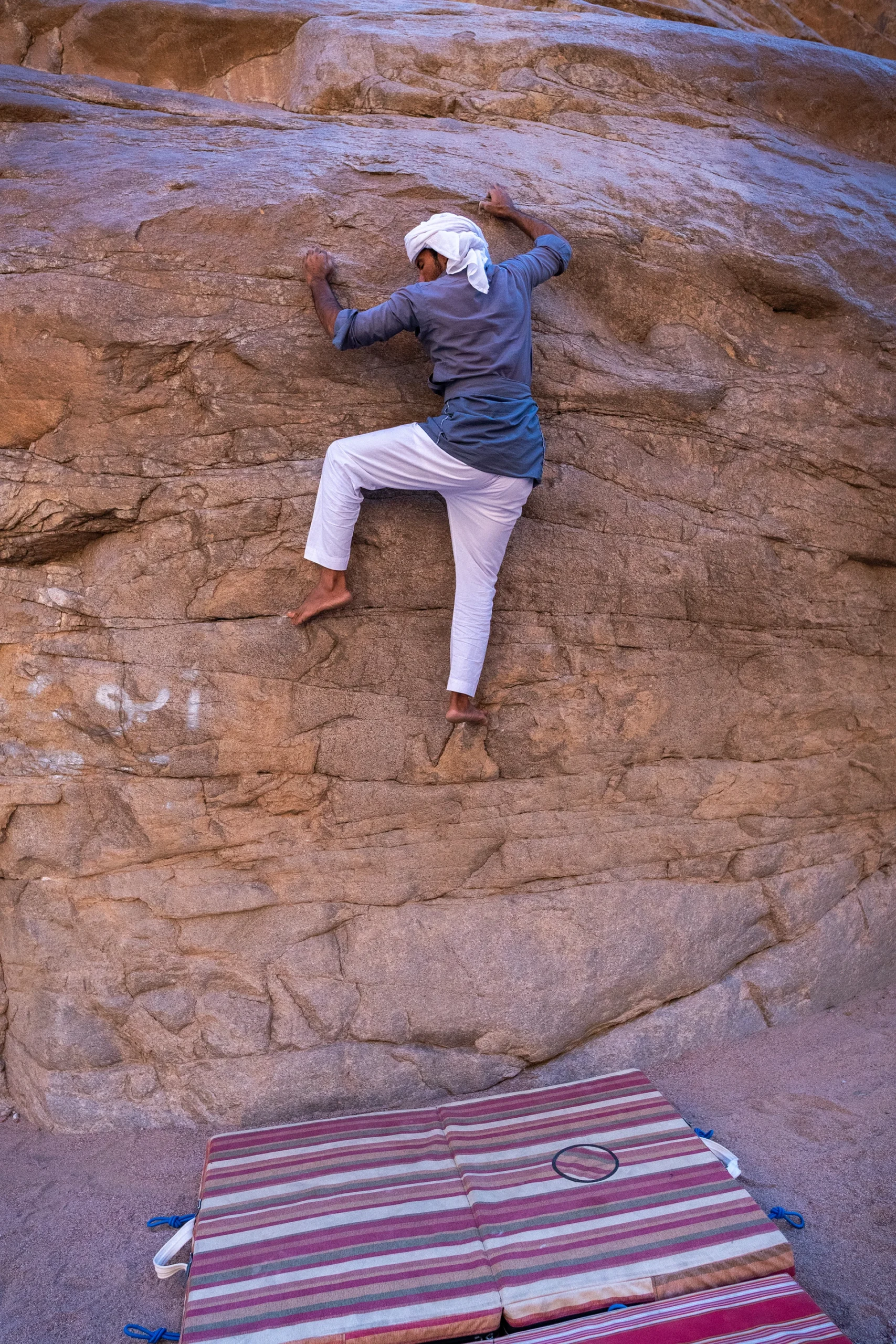 Klimmer in blauwe broek op ruwe rotswand