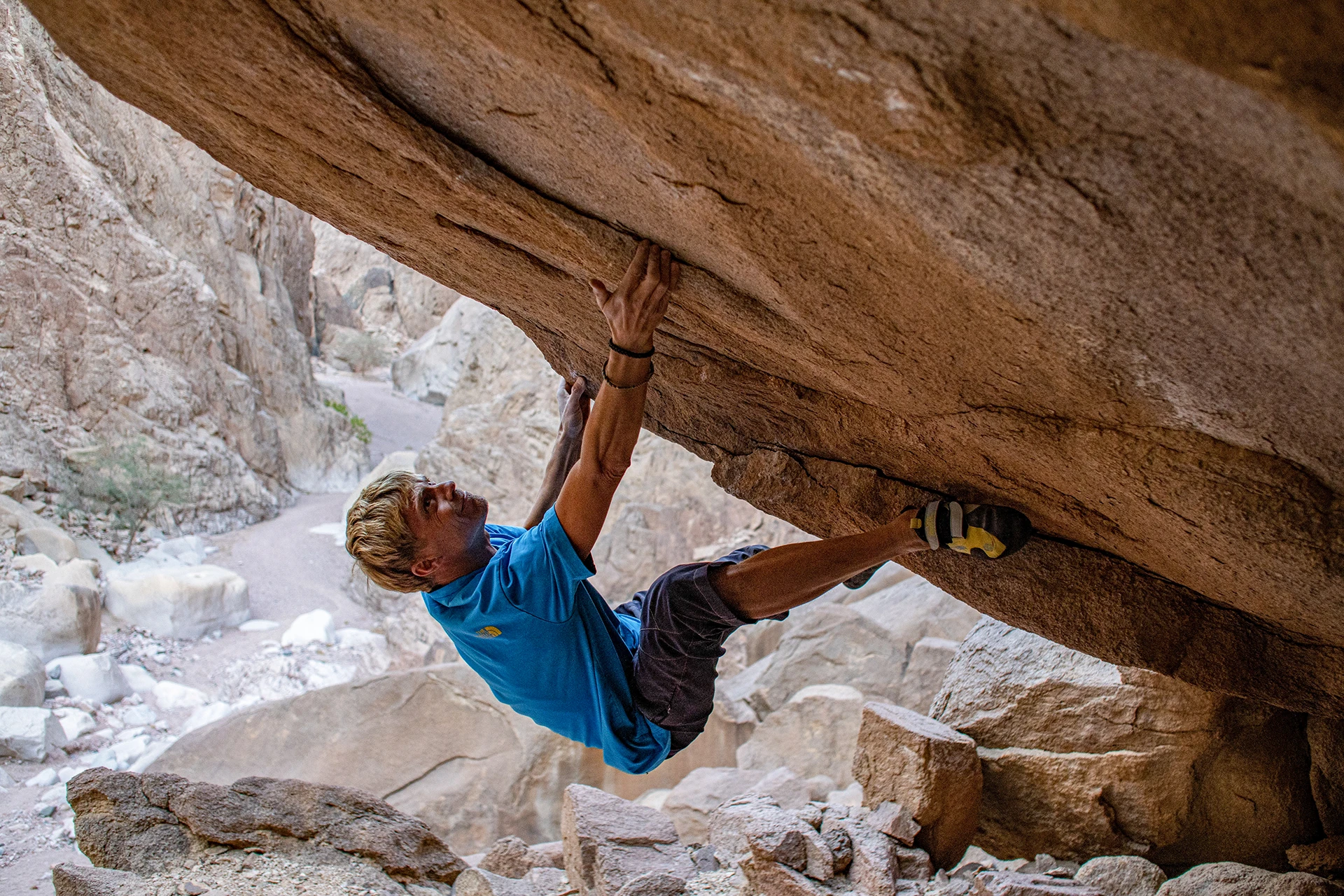 Klimmer hangt onder een overhangende rots