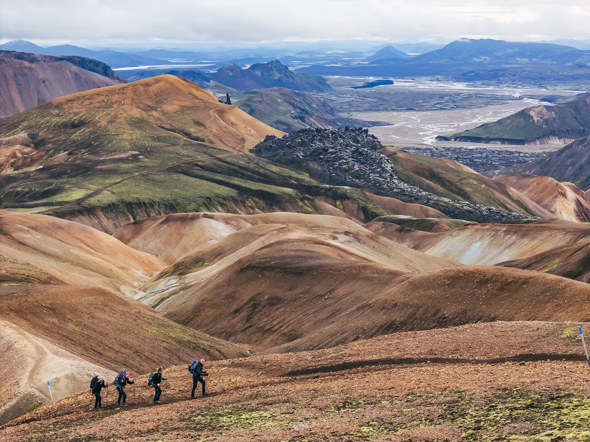 Wandelaars lopen door golvend rhyolietlandschap