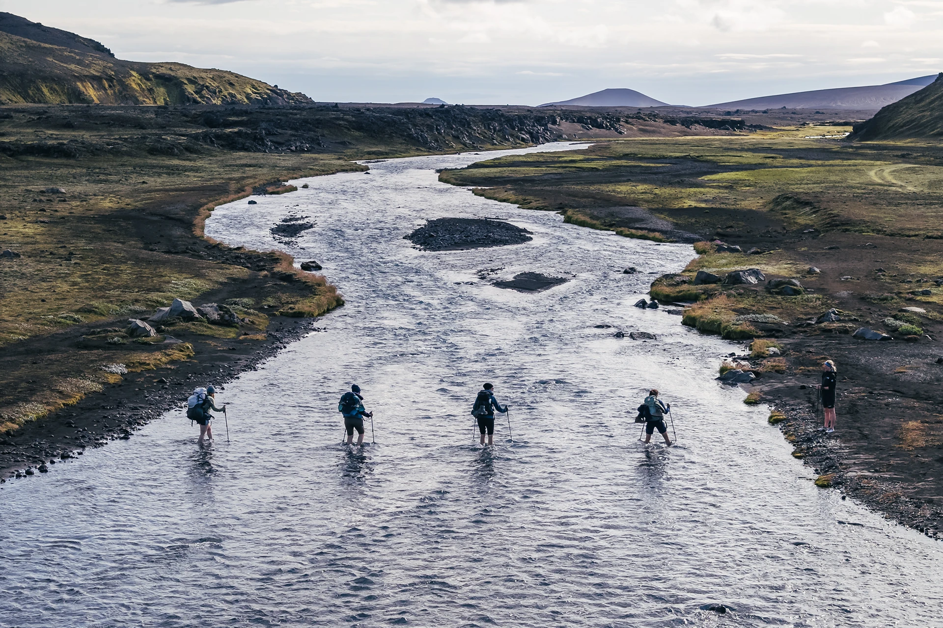 Vier wandelaars steken een brede rivier over