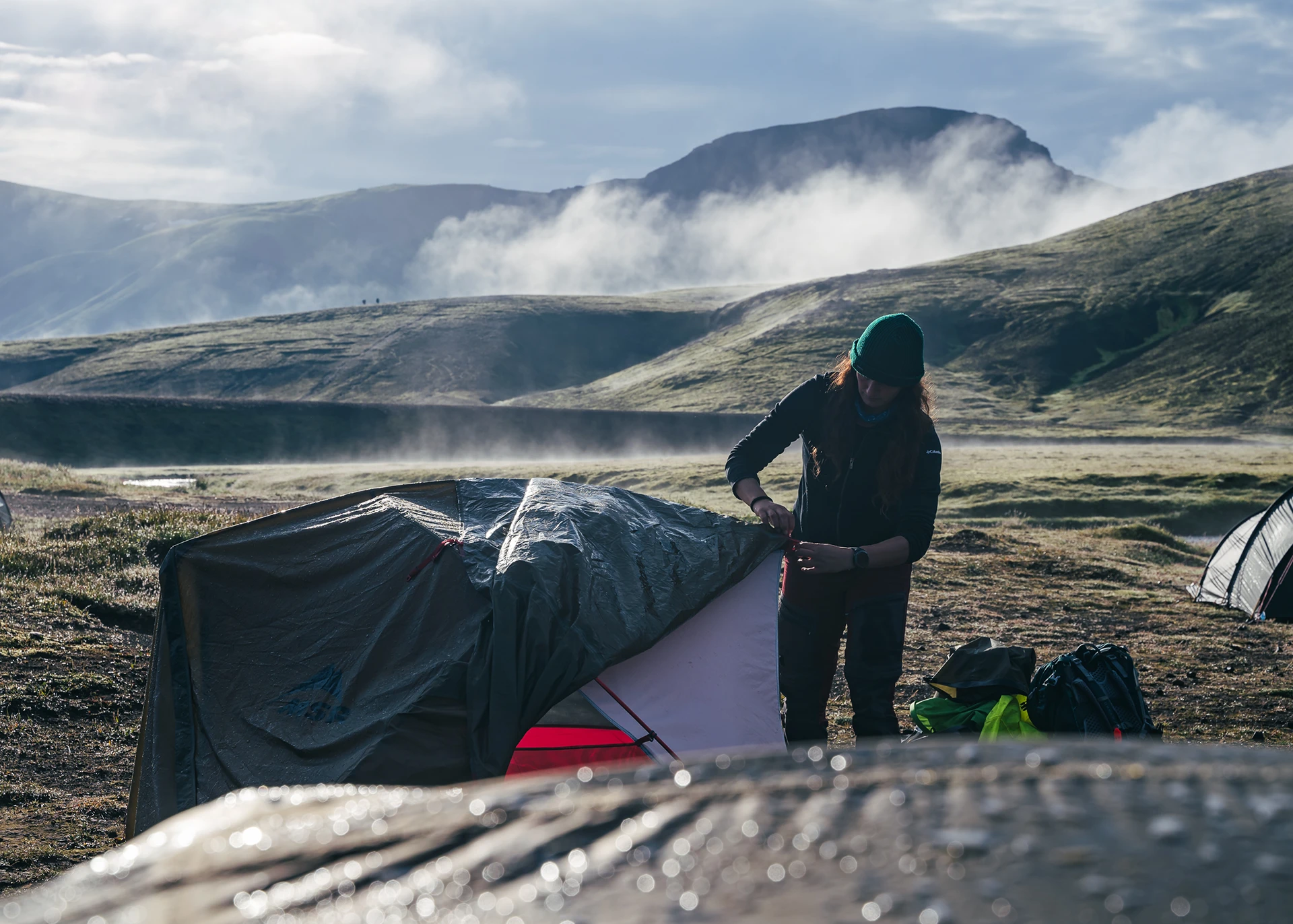 Kampeerders bij tent in winderig landschap