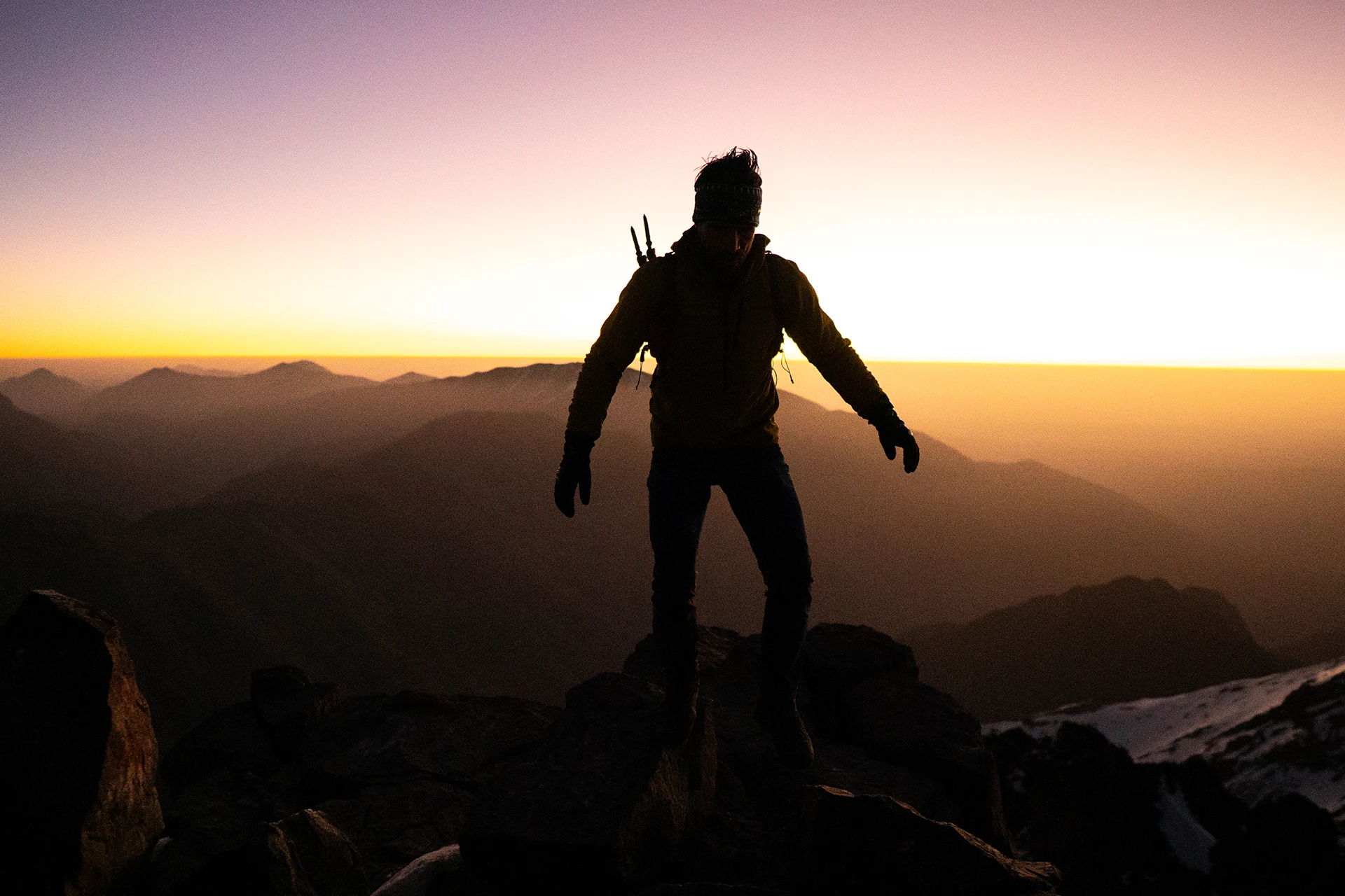 Silhouet van wandelaar op een rots bij zonsondergang