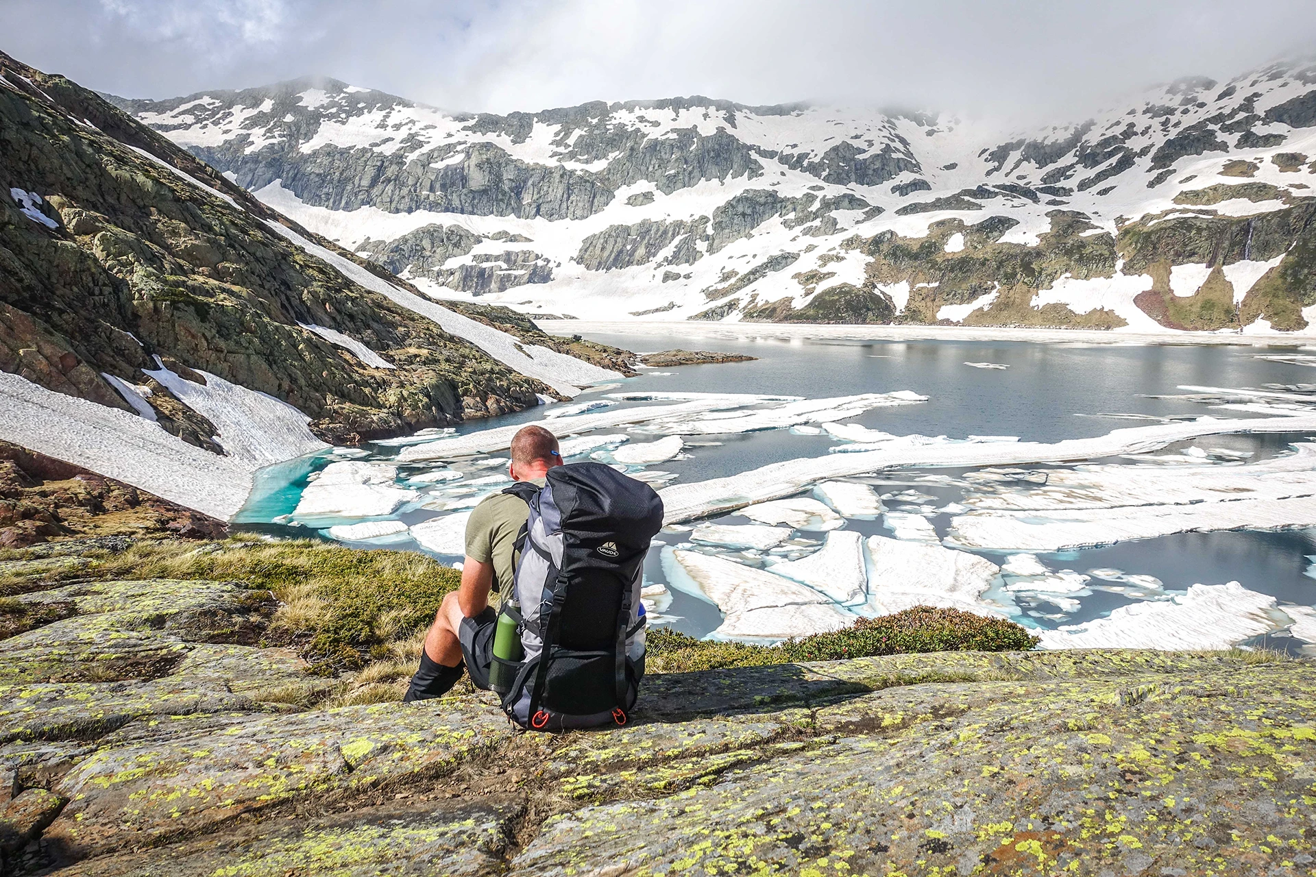 Wandelaar zit bij een ijzig bergmeer met drijvende ijsplaten