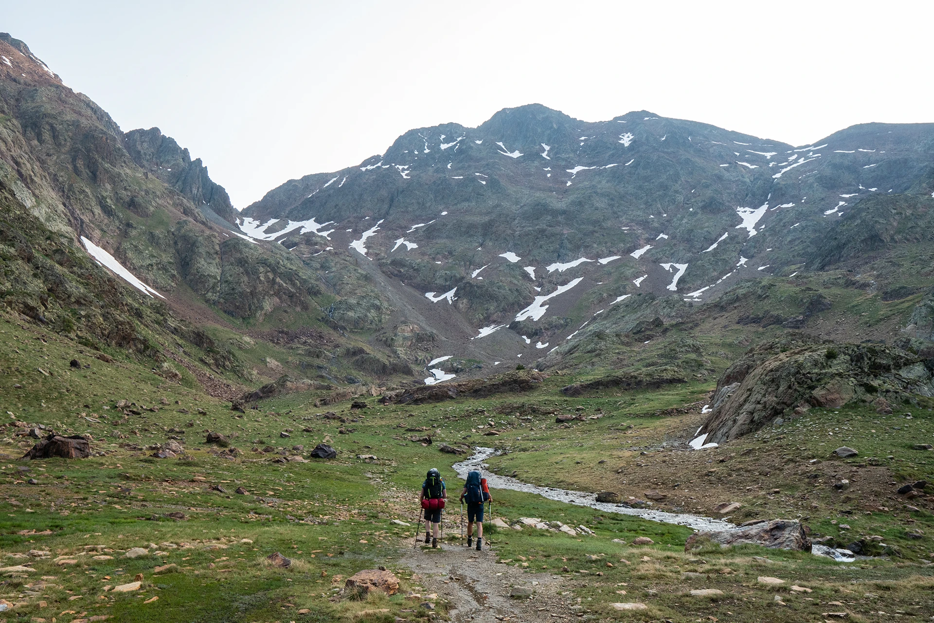 Wandelaars lopen door open vallei met bergen
