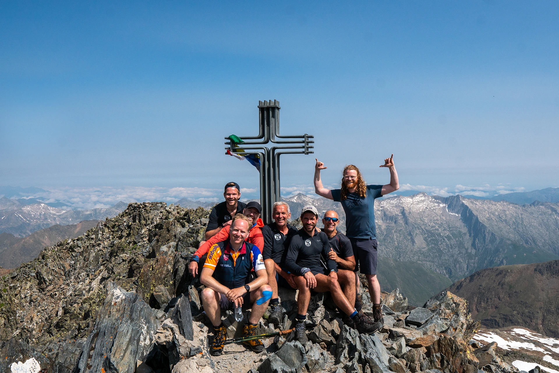 Groep wandelaars bij groot kruis op bergtop