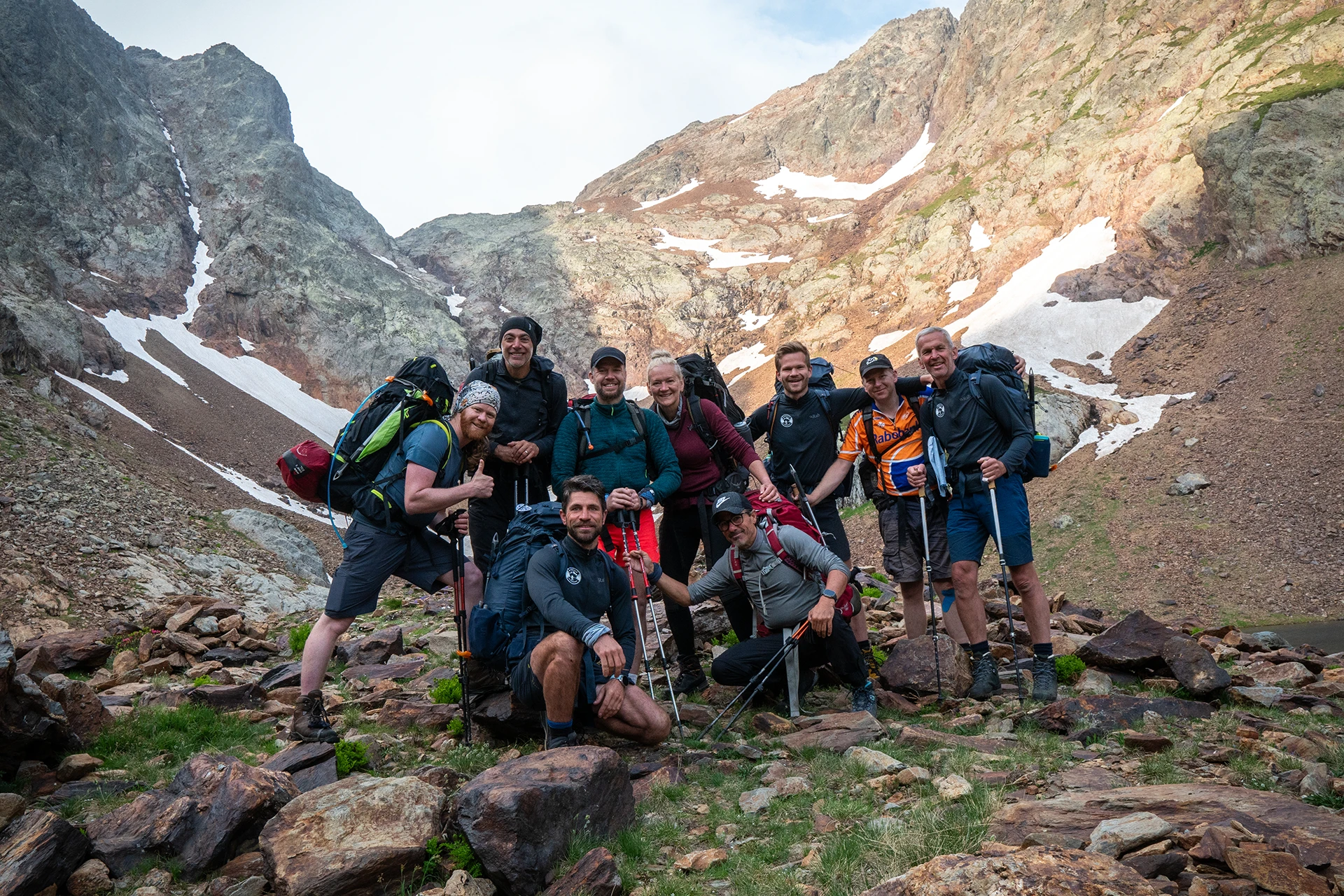 Groep hikers poseert met rugzakken in rotsachtig sneeuwgebied