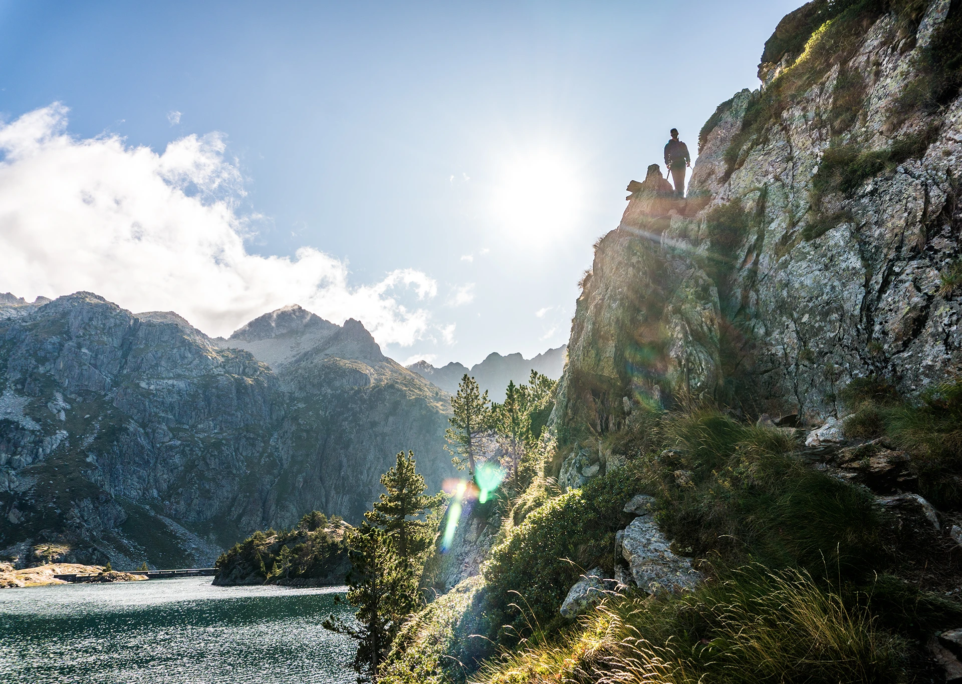 Zon schijnt langs smalle rotswand boven blauw meer