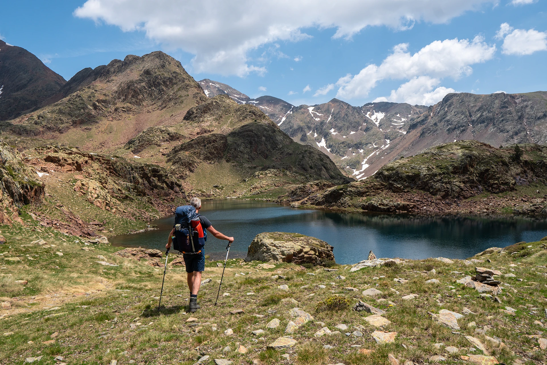 Wandelaar kijkt uit over blauw bergmeer