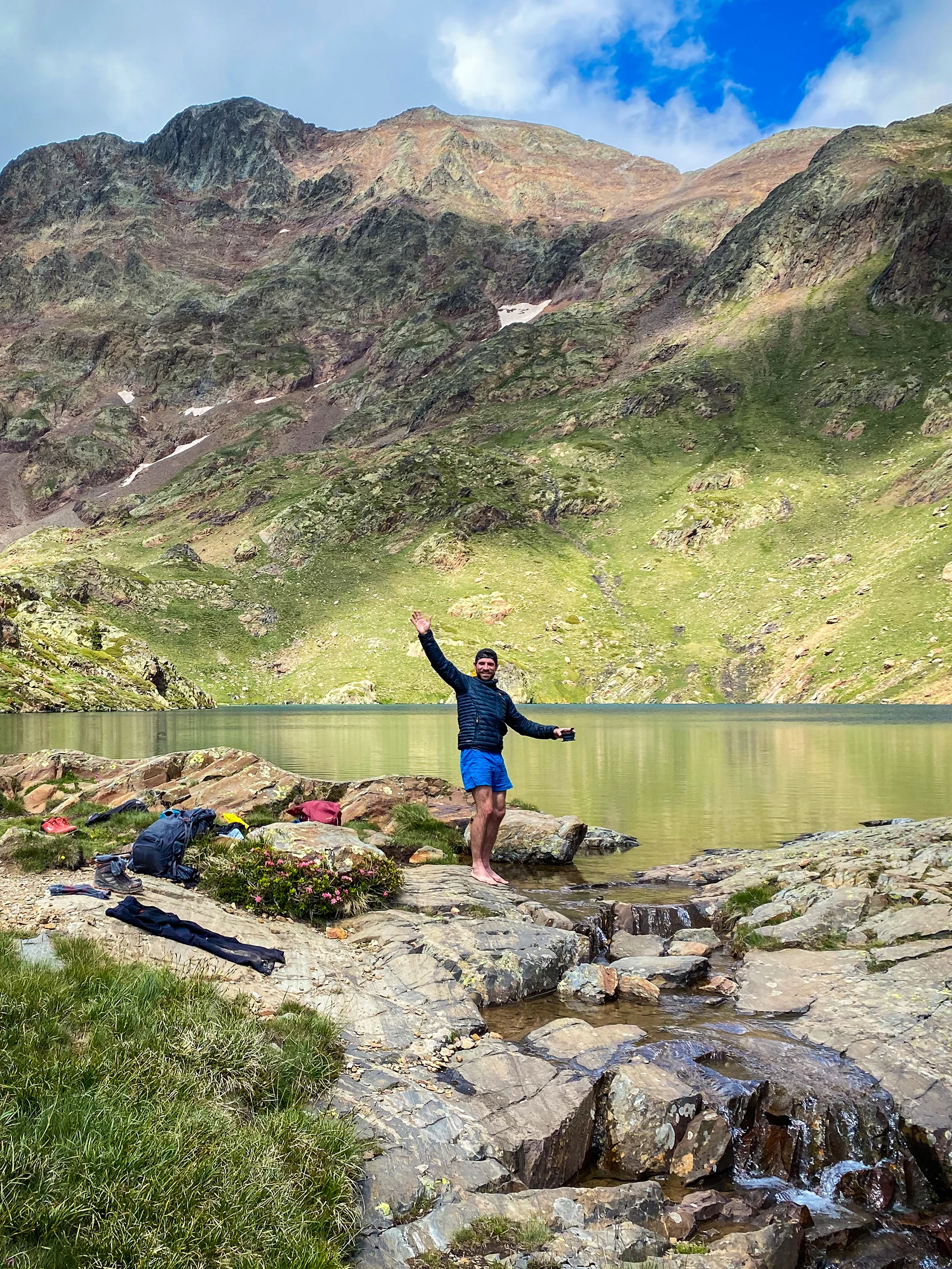 Wandelaar staat met open armen boven een bergmeer