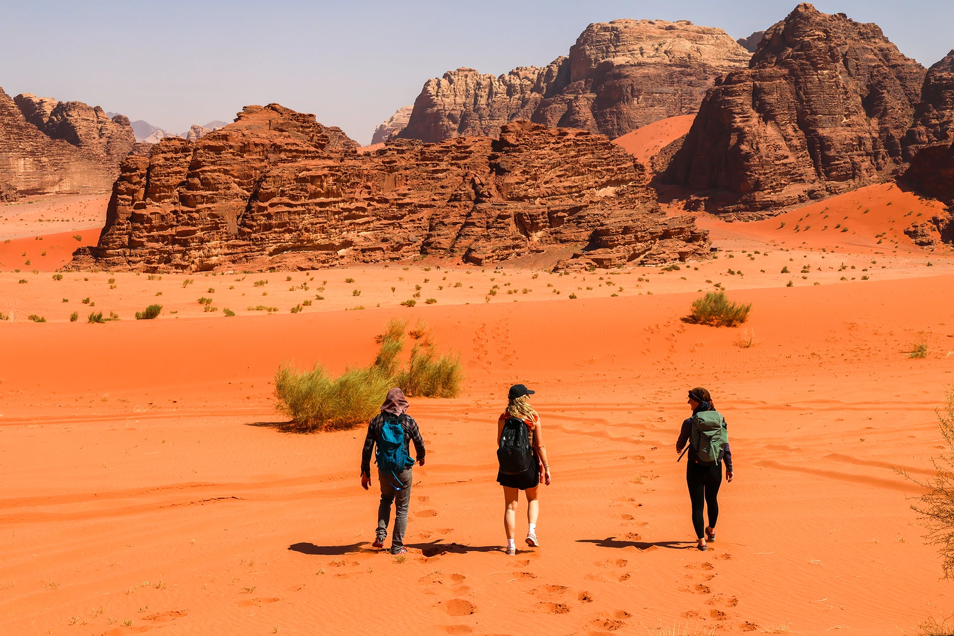 Hikers lopen door fel oranje woestijnzand