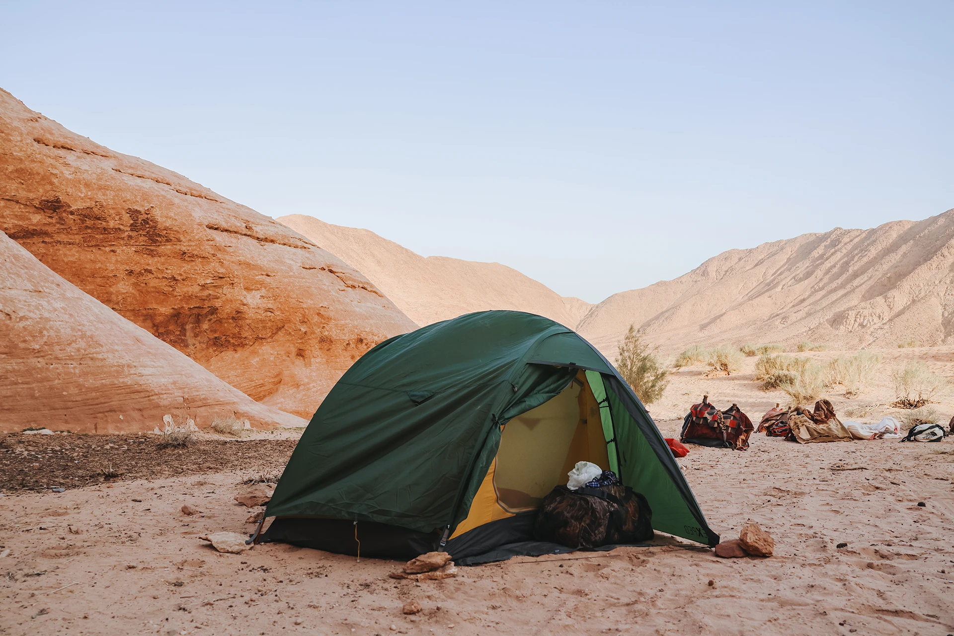 Groene tent opgezet tussen zand en rotsen
