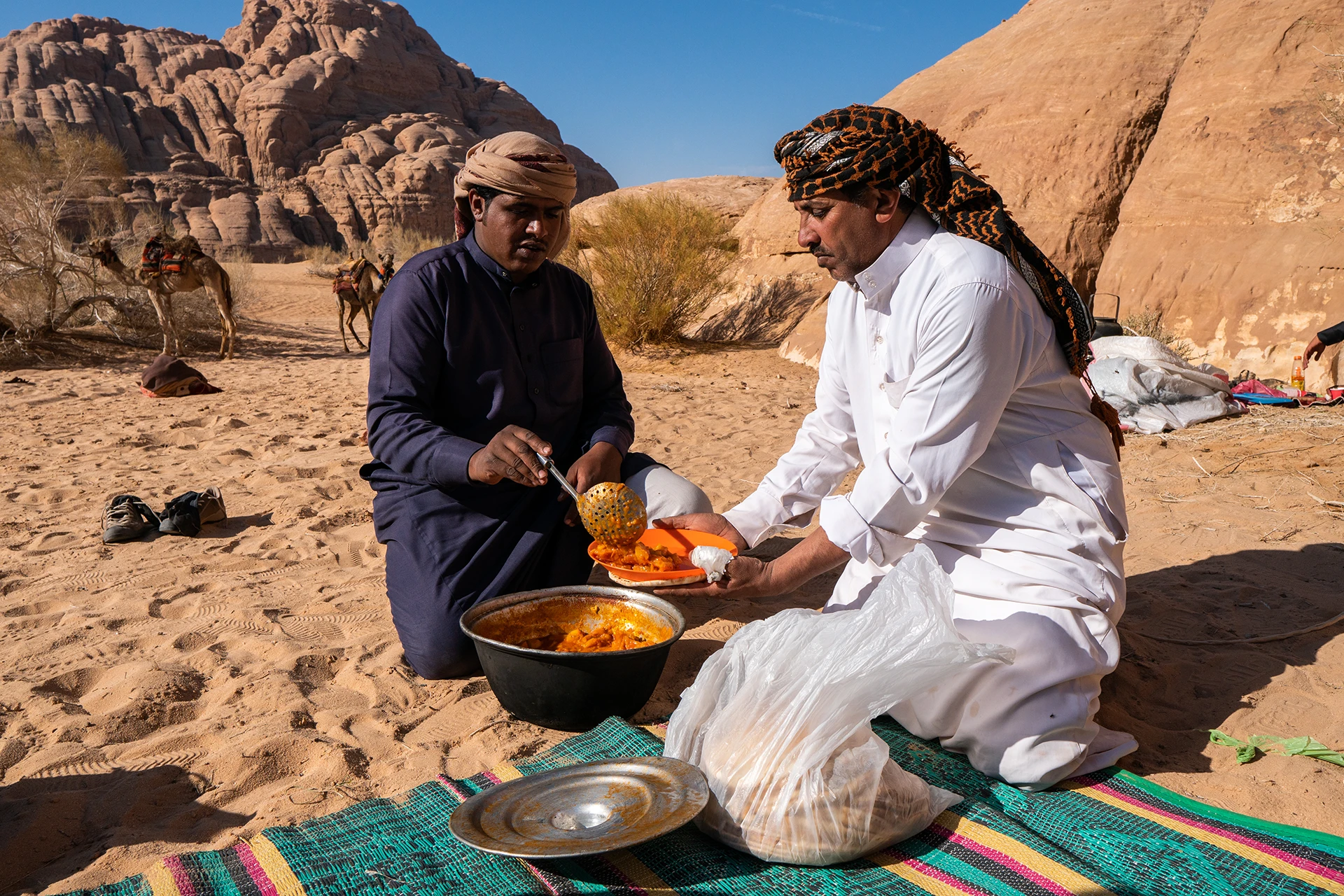 Twee mensen eten op een kleed in de woestijn