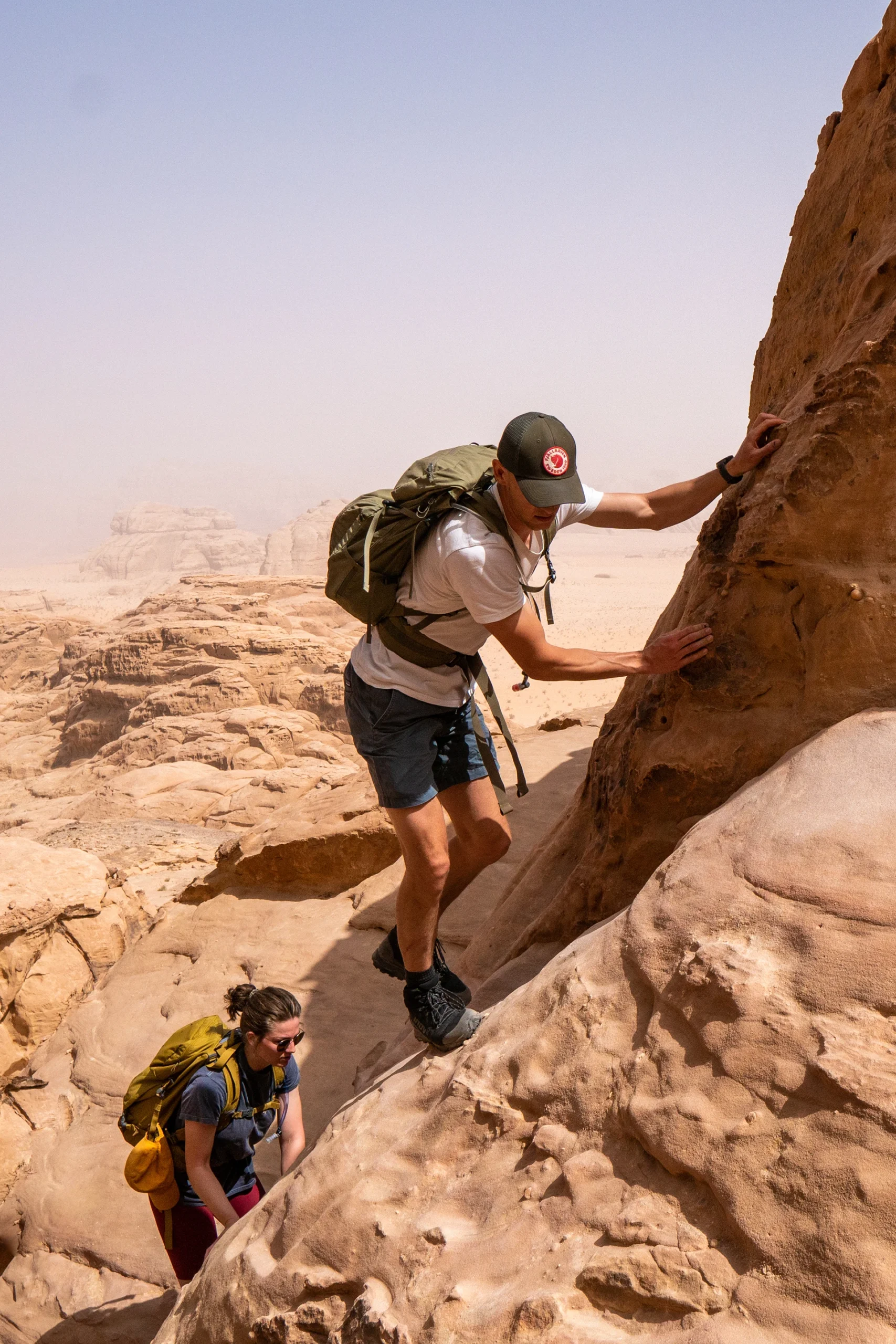 Wandelaar klimt omhoog langs rotswand in de woestijn