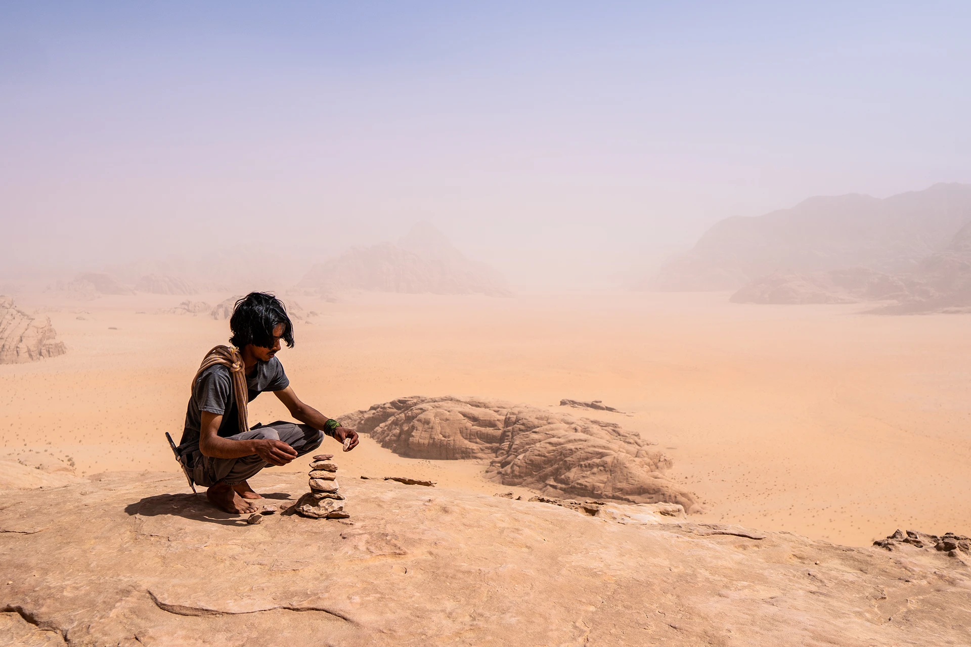 Hiker rust op rots boven zandige woestijnvlakte