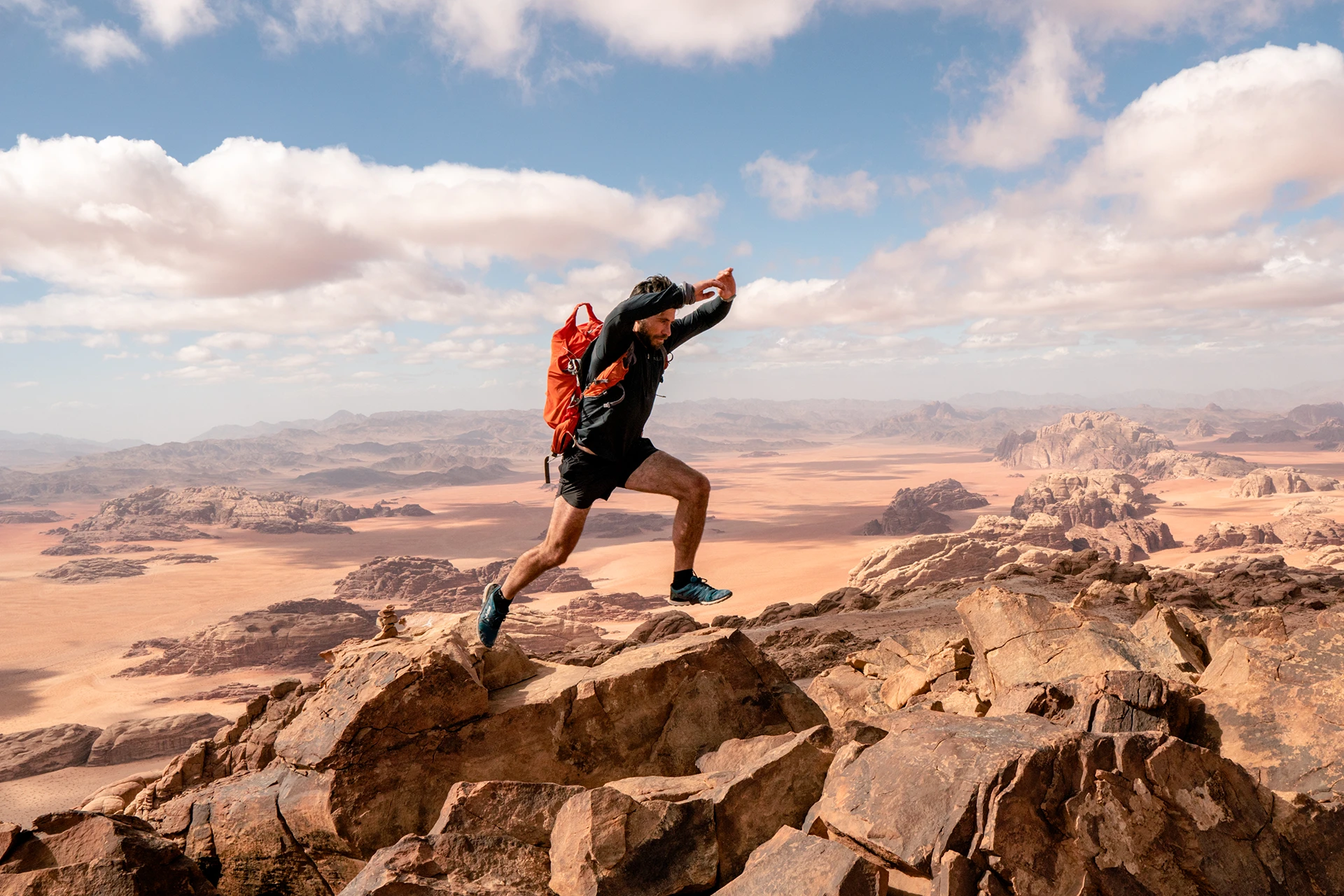 Hiker springt over rotsrand met woestijnuitzicht