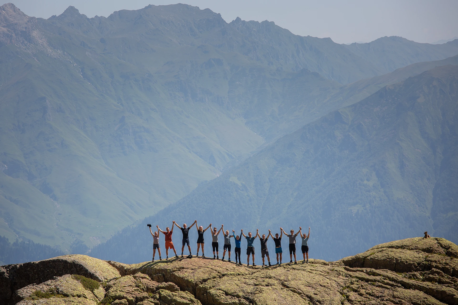 Groep hikers loopt over een rotsplateau met hoge bergen achter
