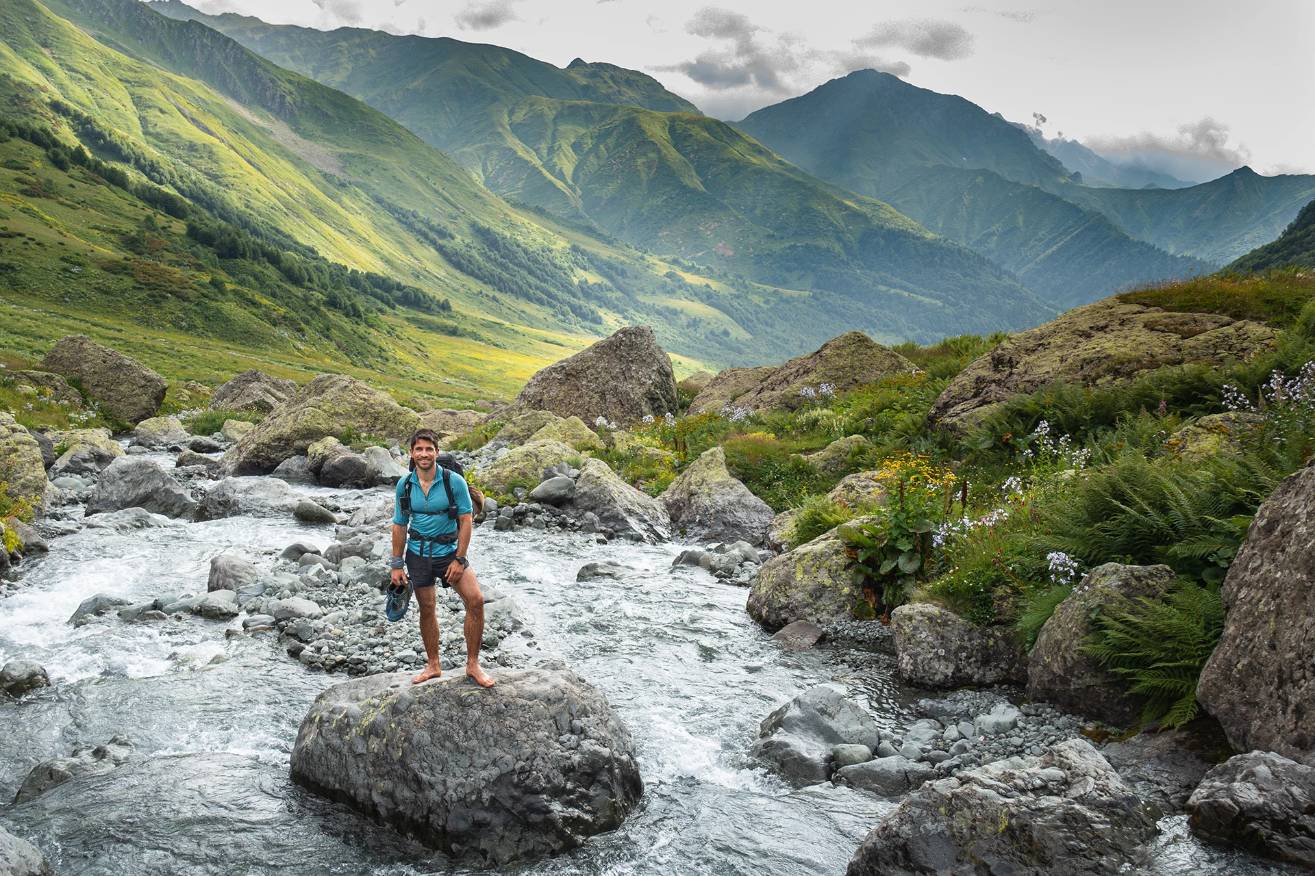 Wandelaar steekt rivier over in groene vallei