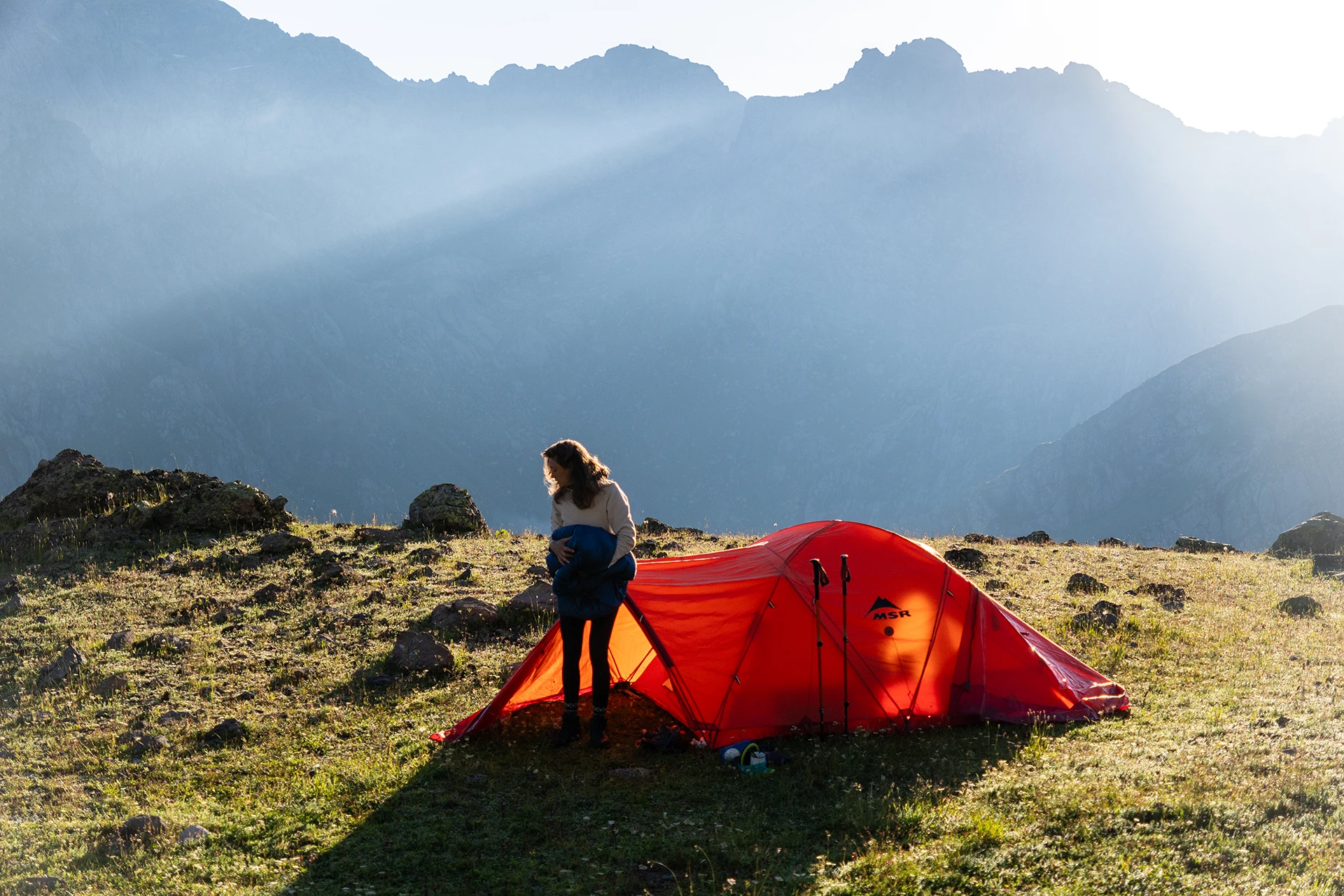 Vrouw zet rode tent op in ochtendlicht