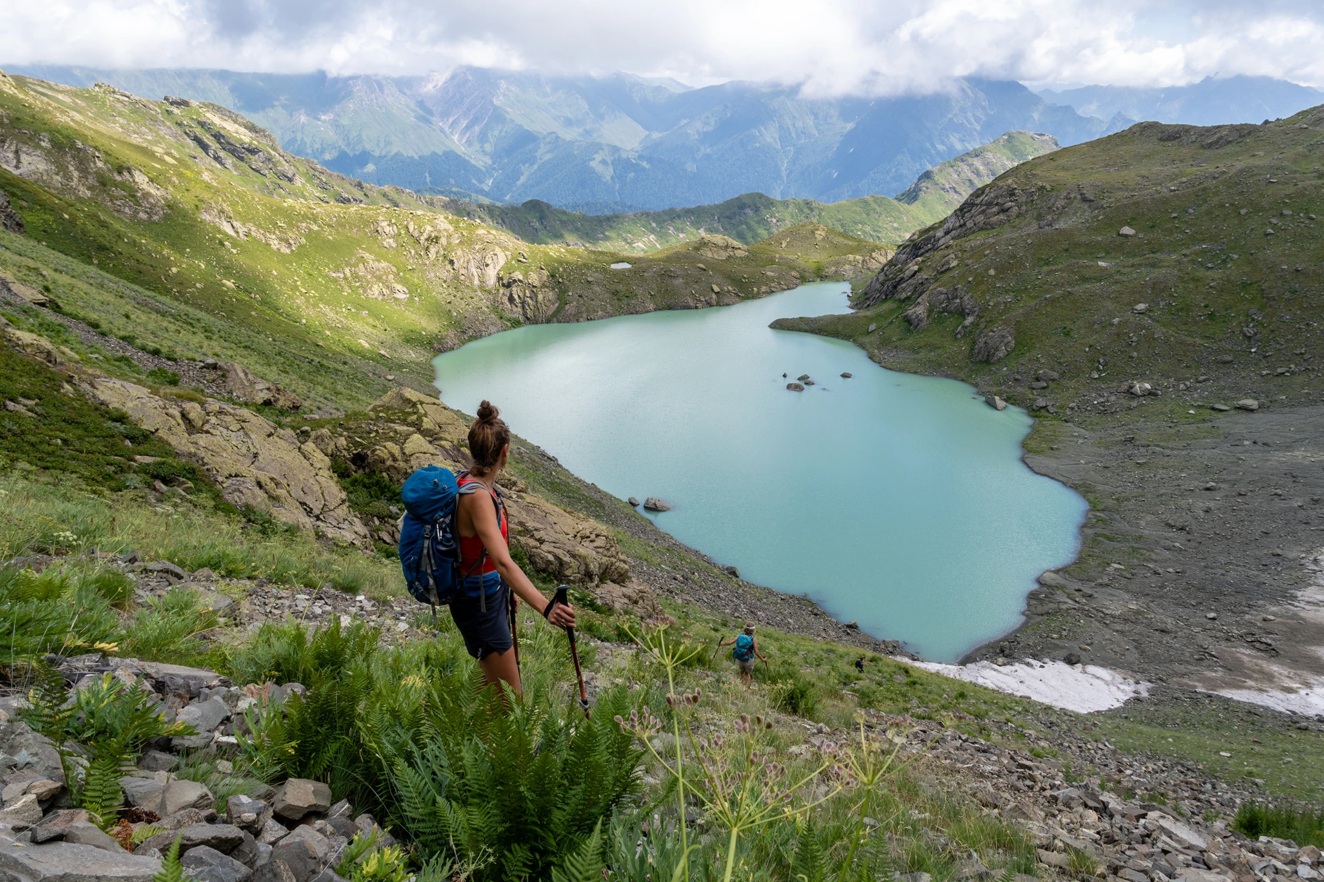 Wandelaar kijkt uit over turquoise bergmeer