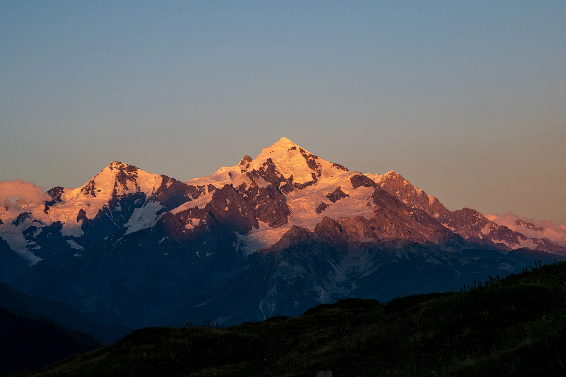 Bergtoppen kleuren oranje in avondlicht
