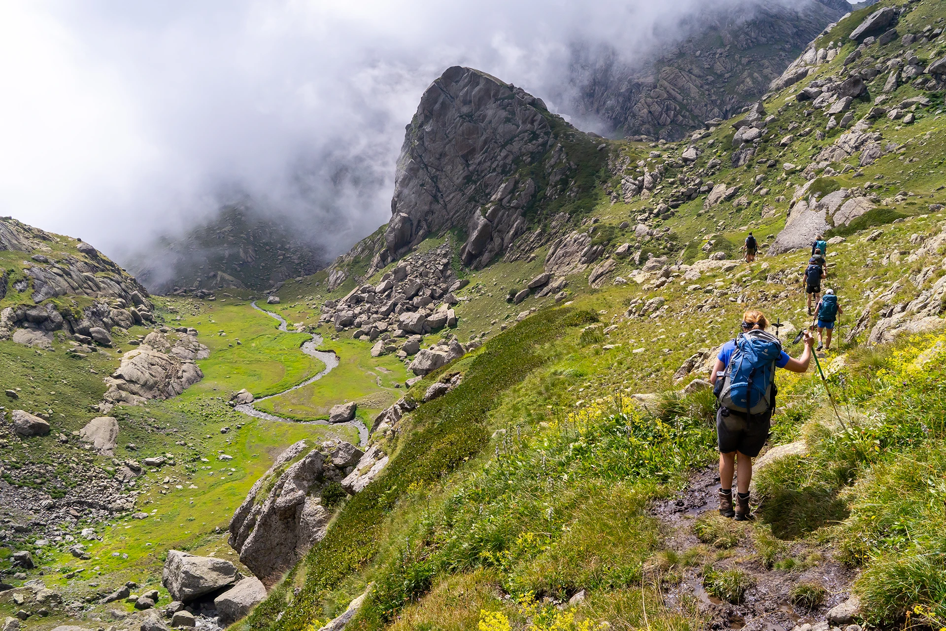 Groene alpenvallei met mist tussen hoge pieken