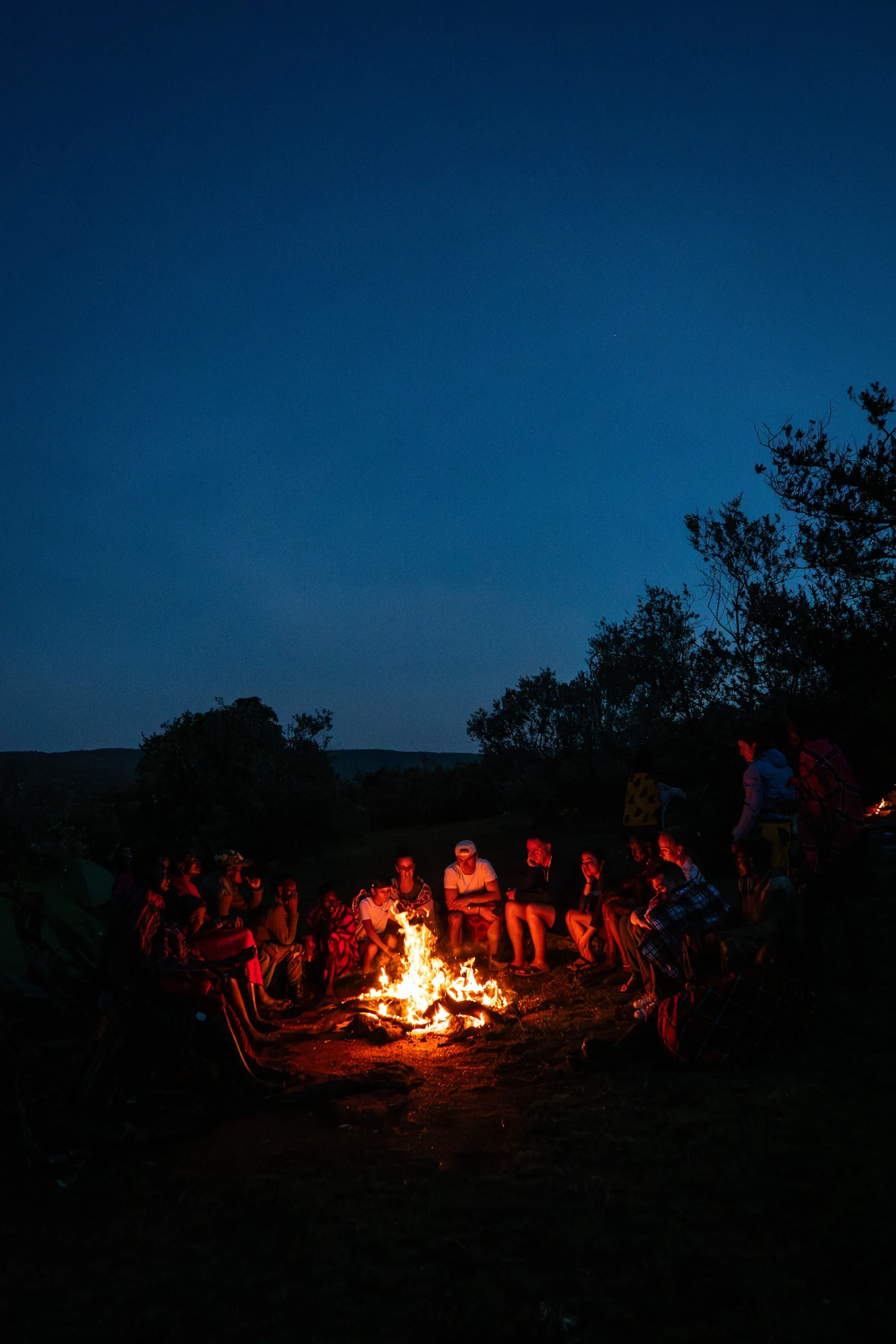 Avondscène met mensen verzameld rond een kampvuur