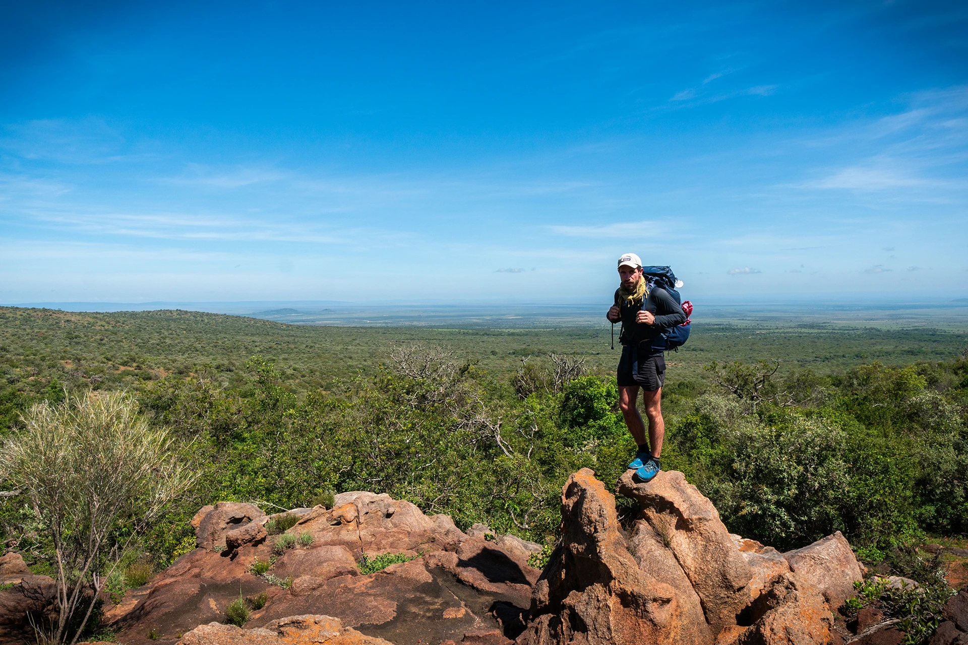 Hiker die op een rots staat met uitzicht over een groen landschap