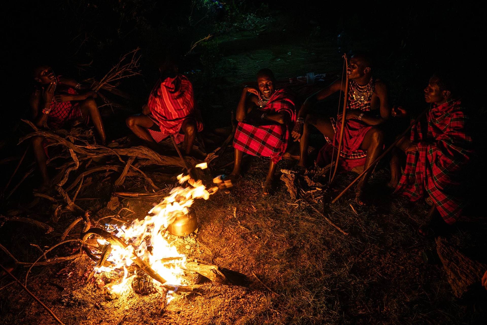 Mensen rond een kampvuur in het donker in een bosrijke omgeving