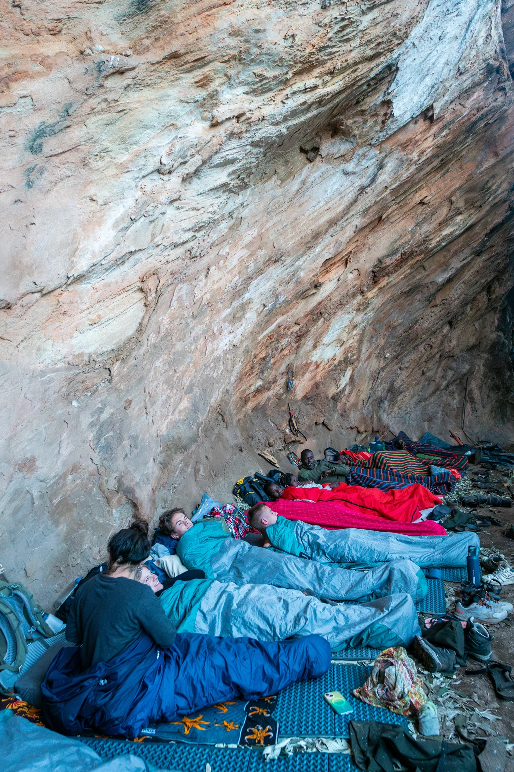 Mensen slapen in blauwe slaapzakken onder rotswand