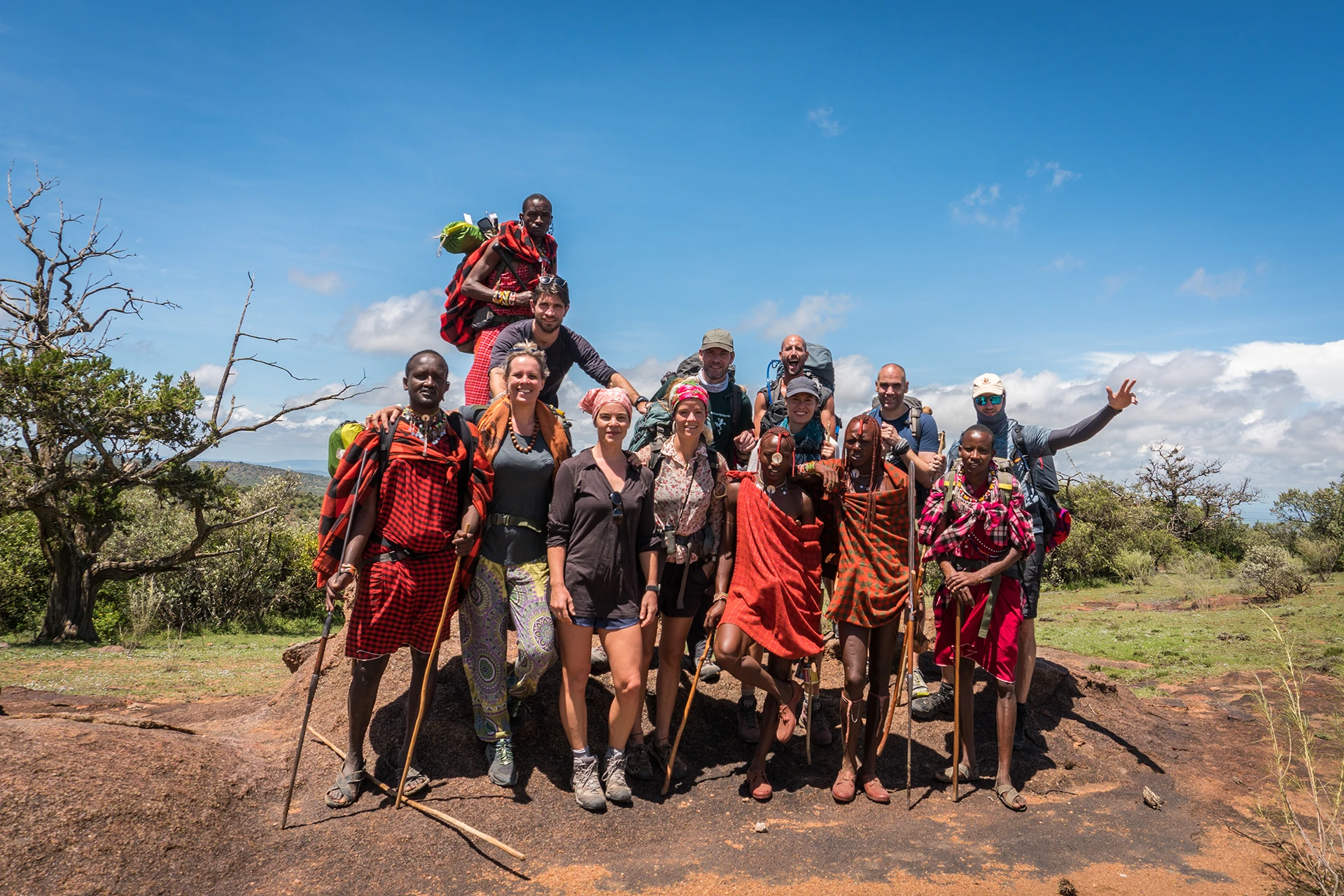 Groep mensen loopt in traditionele kleding door savanne