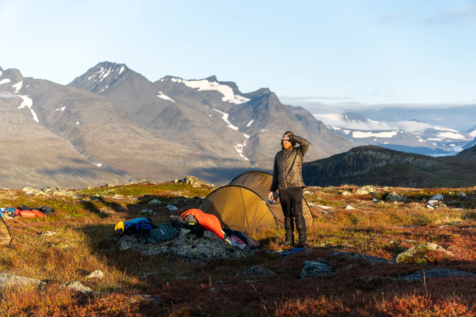 Kampplaats met tent en hiker in een bergachtig gebied