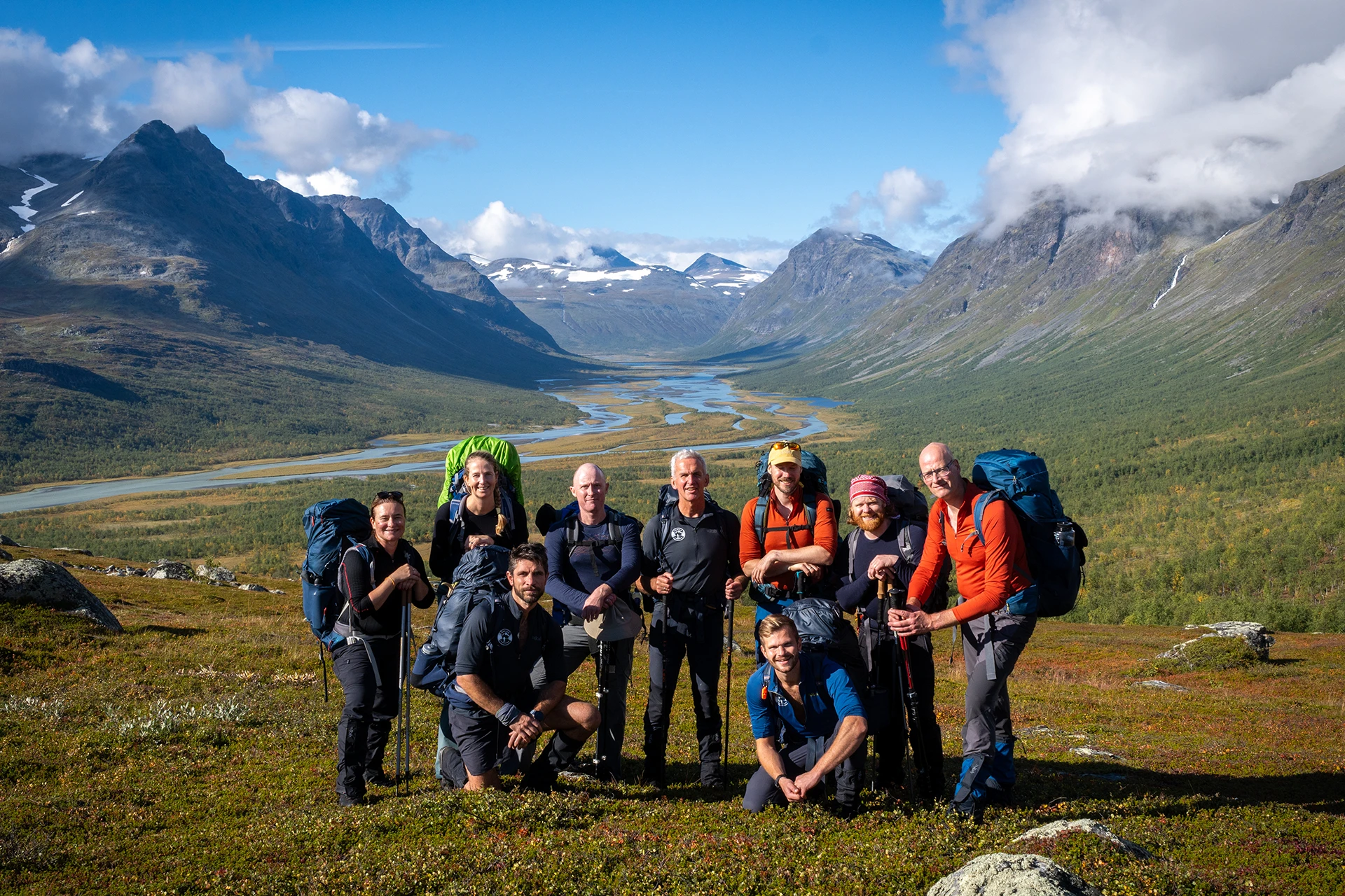 Groep hikers die samen poseert in een breed bergdal