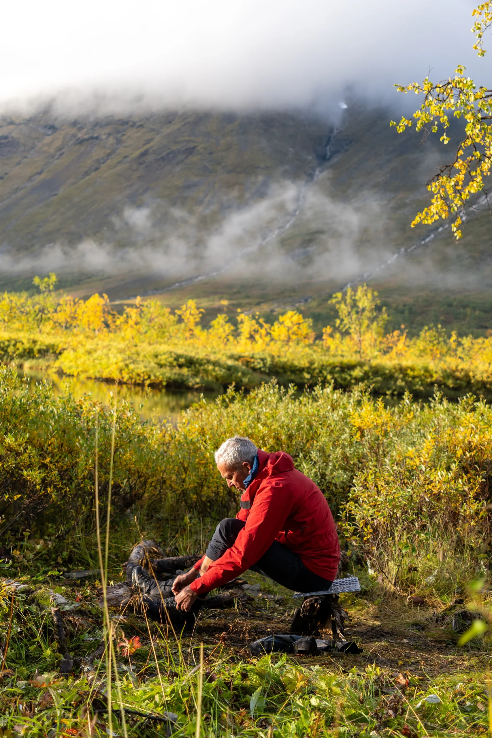 Persoon die rust neemt tussen gele bladeren in een berggebied