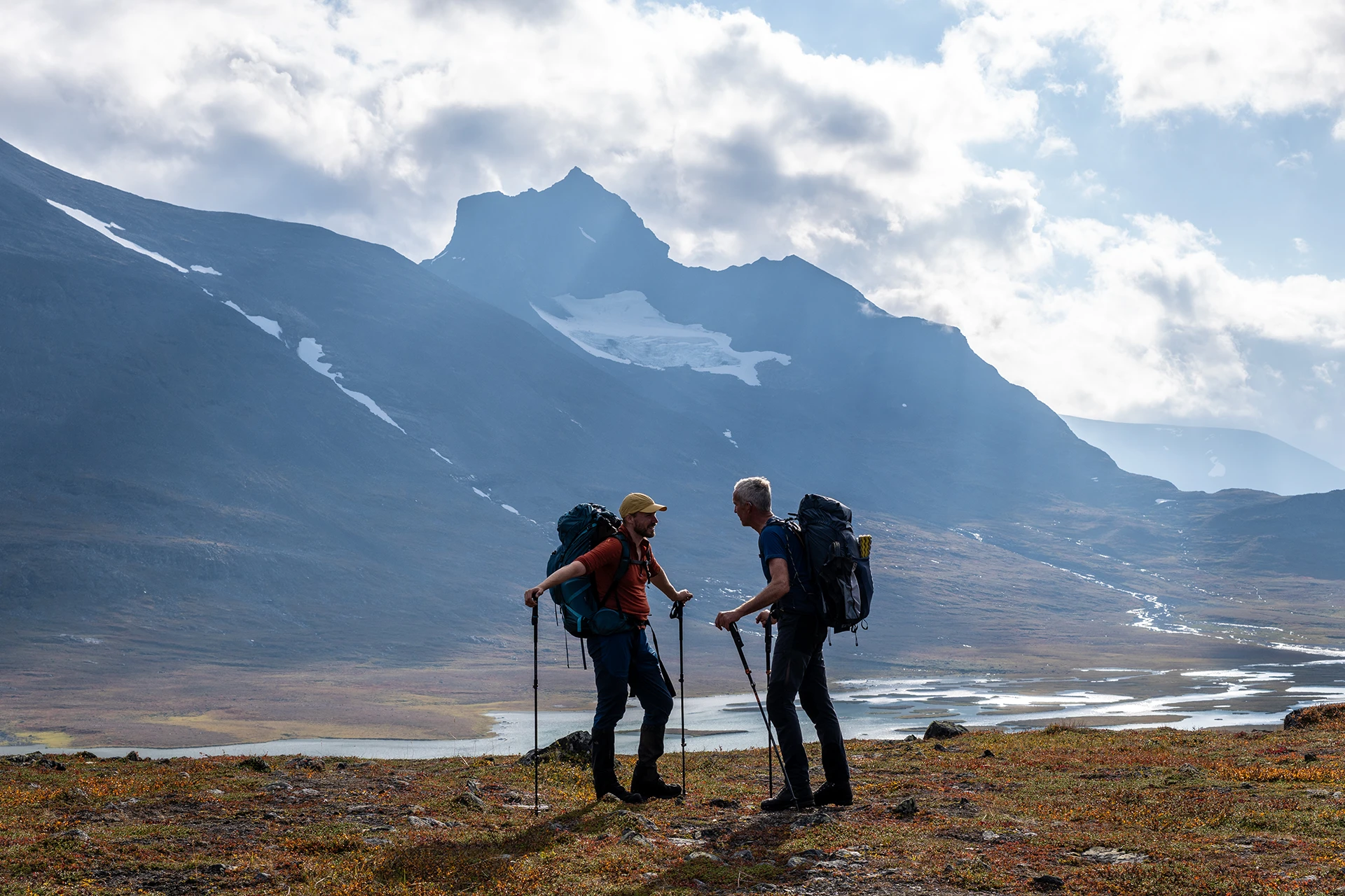 Drie hikers die op een bergtop staan met diepe valleien om hen heen