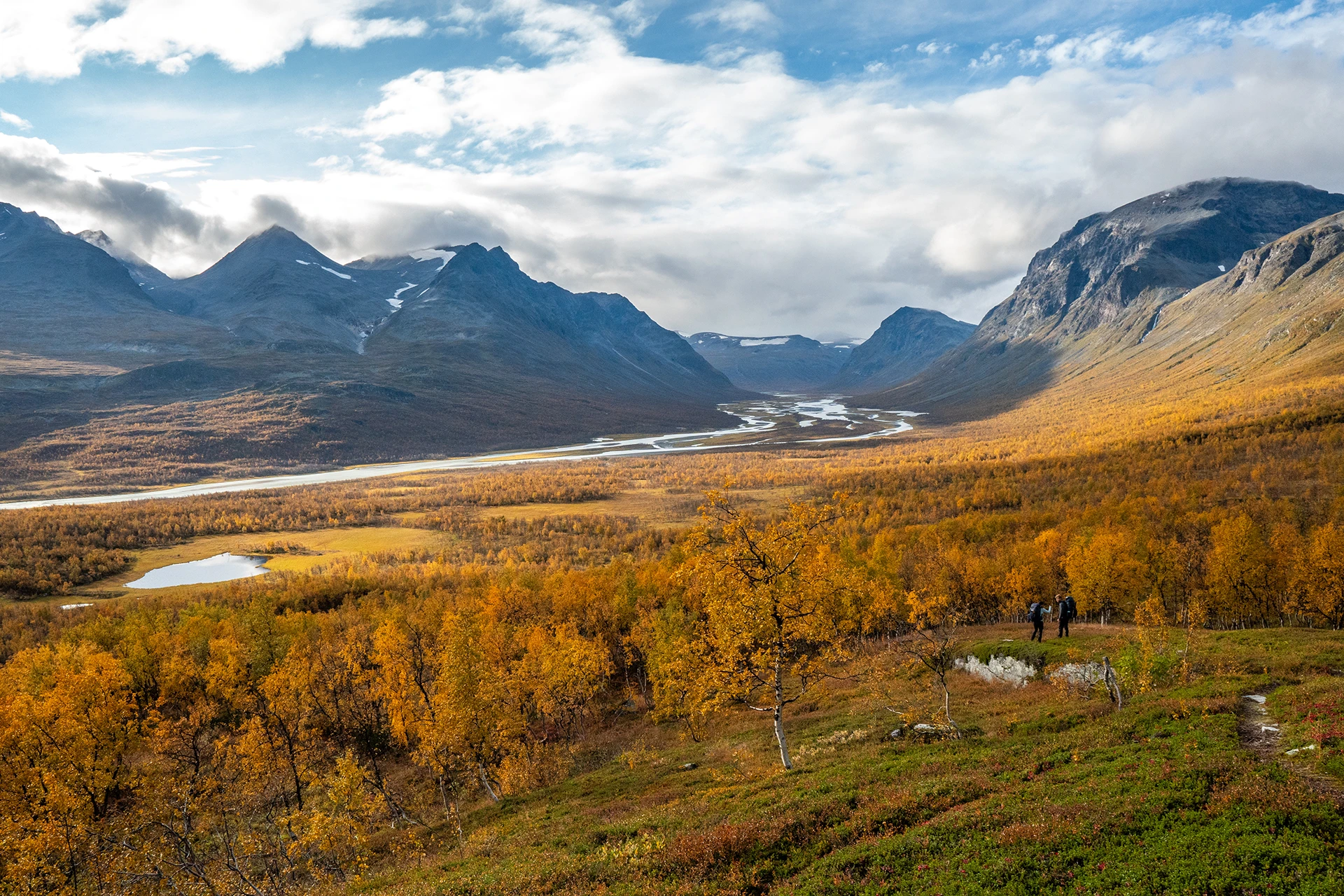 Uitzicht op een brede vallei met herfstkleuren en hoge bergen