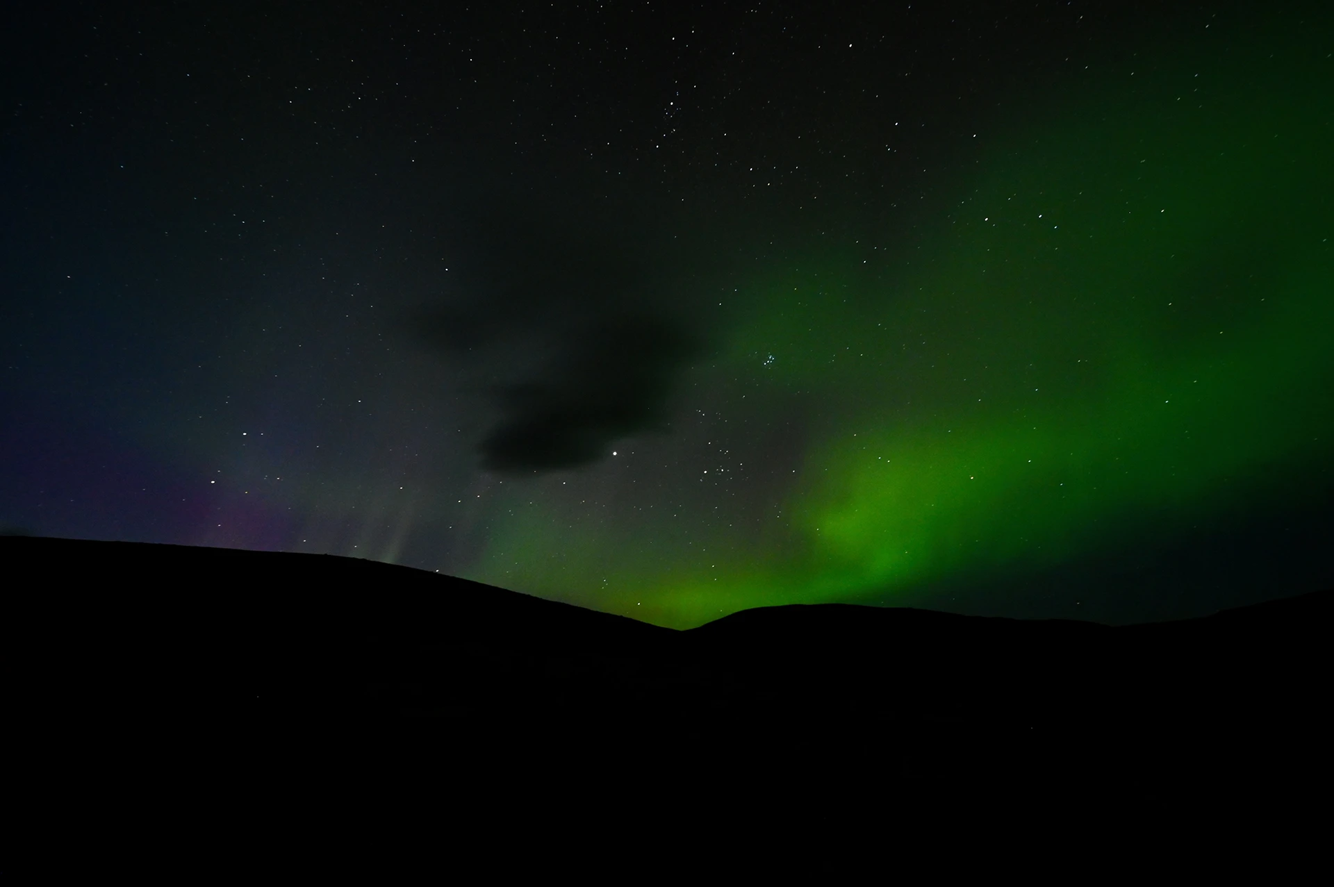 Noorderlicht boven een silhouet van een berg