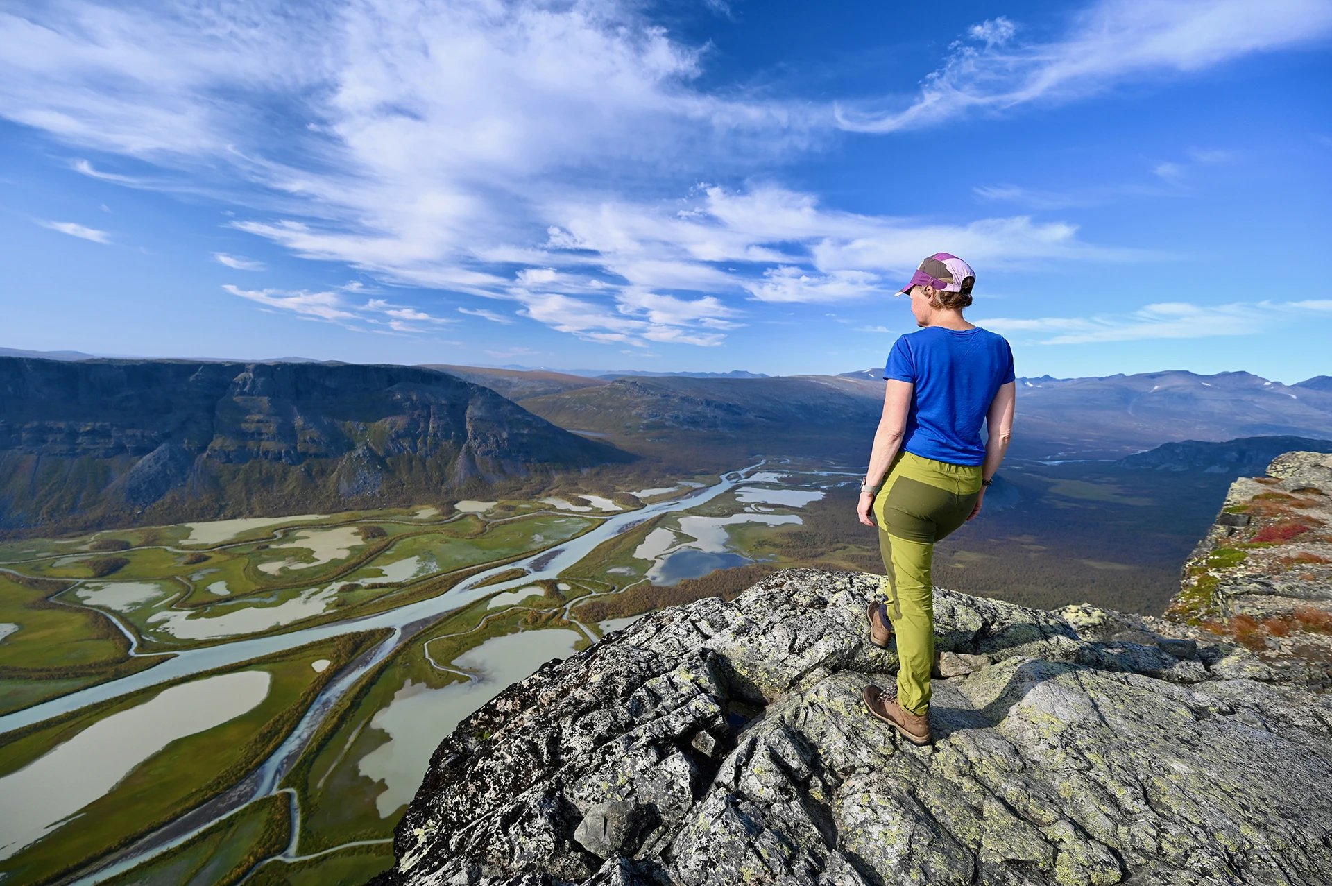 Hiker die op een rots staat met uitzicht over brede valleien