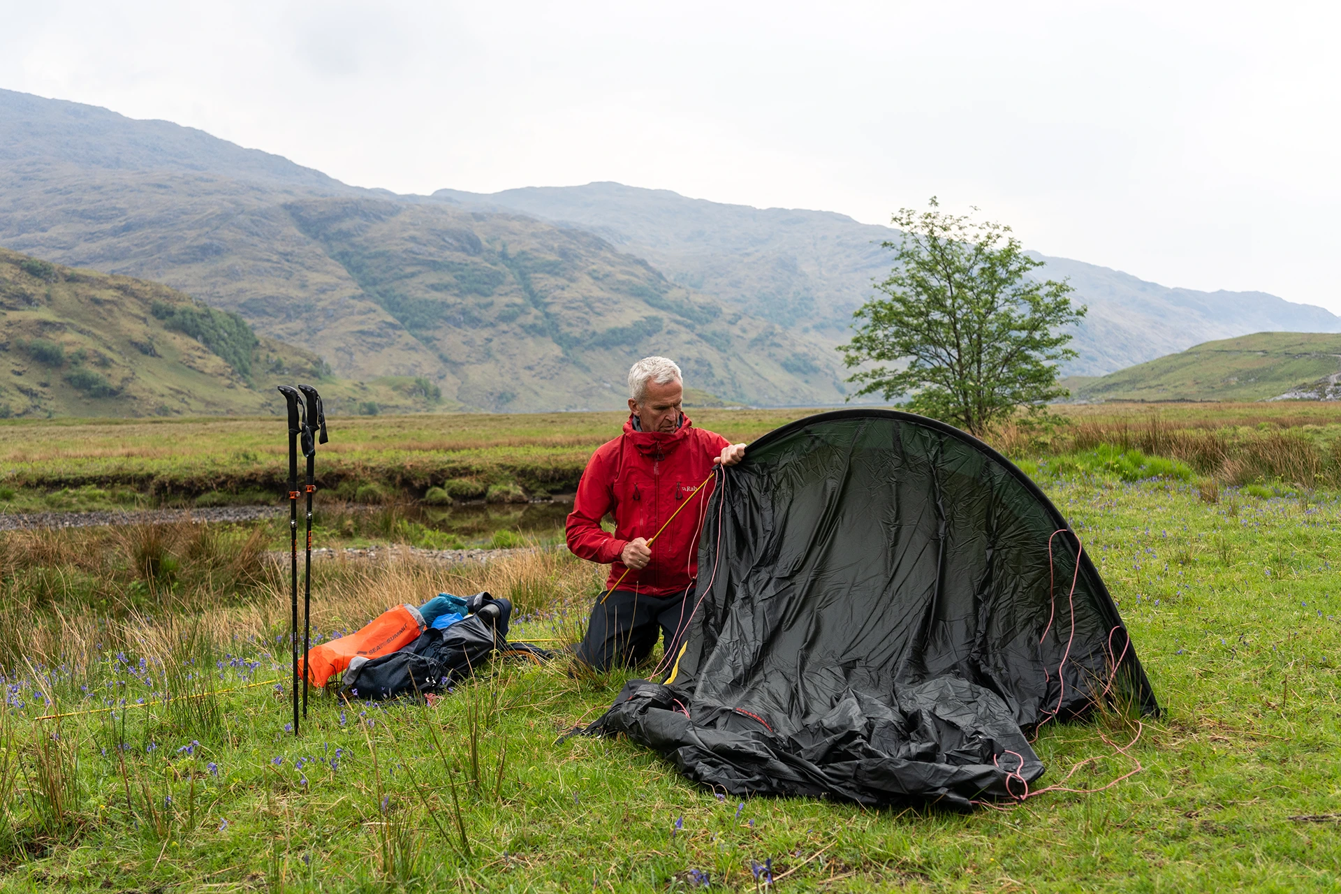 Persoon die een tent opzet op een open grasveld