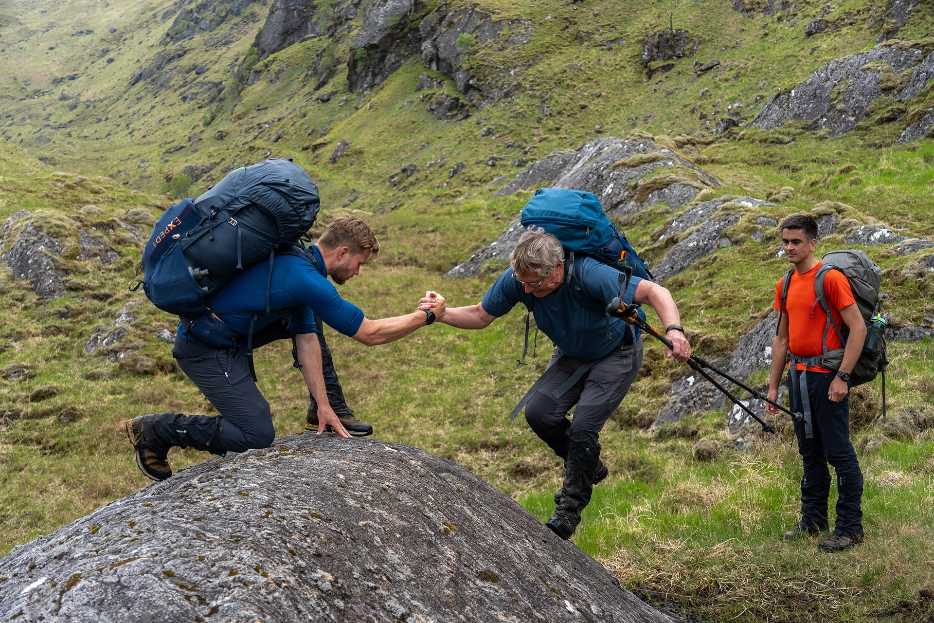 Hiker die een andere hiker helpt bij het klimmen op een rots